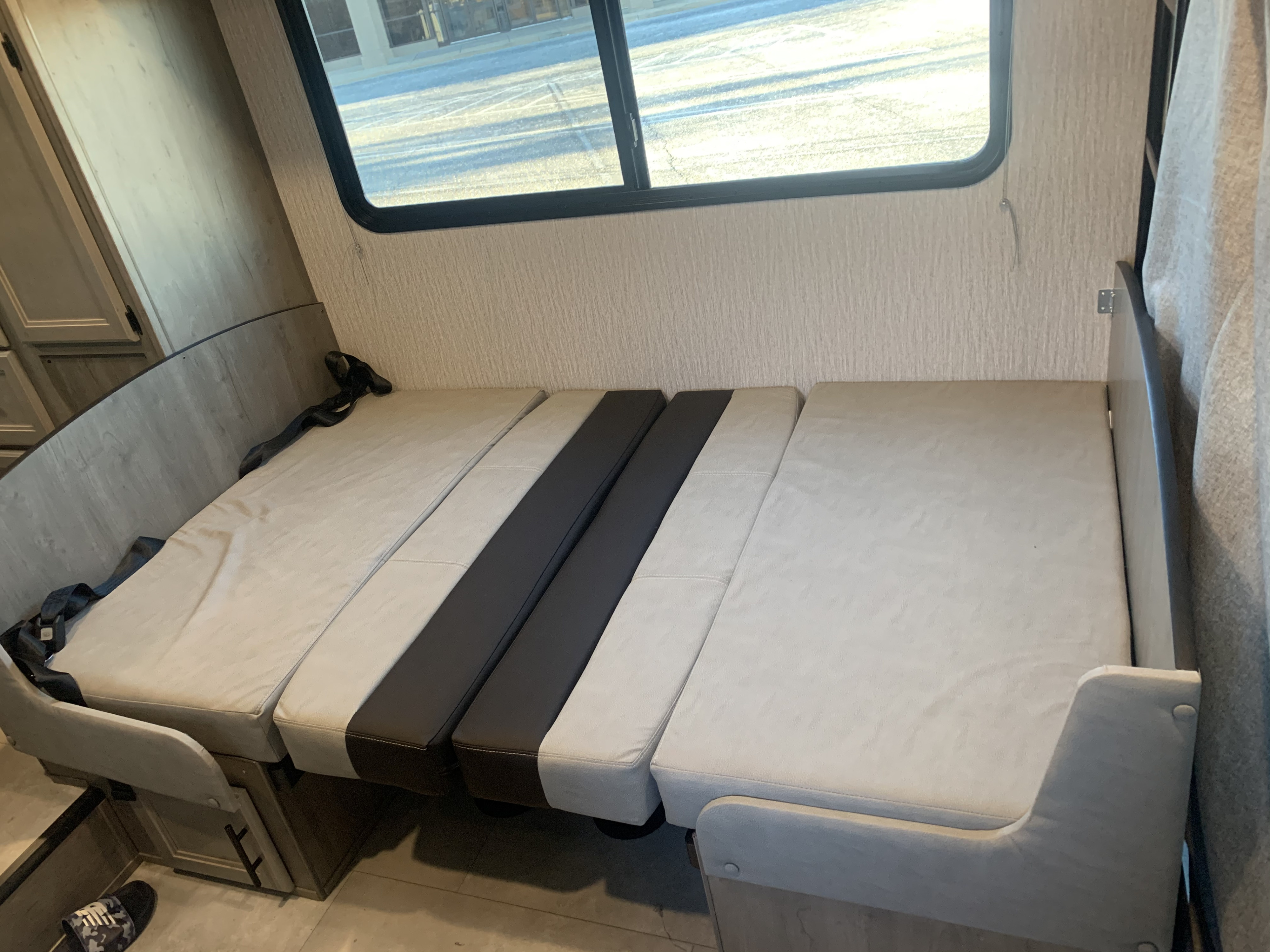 RV rental interior featuring a convertible dinette with light and dark grey cushions and seatbelts, set up for bed conversion.. Forest River Coachmen Cross Trail XL 2022