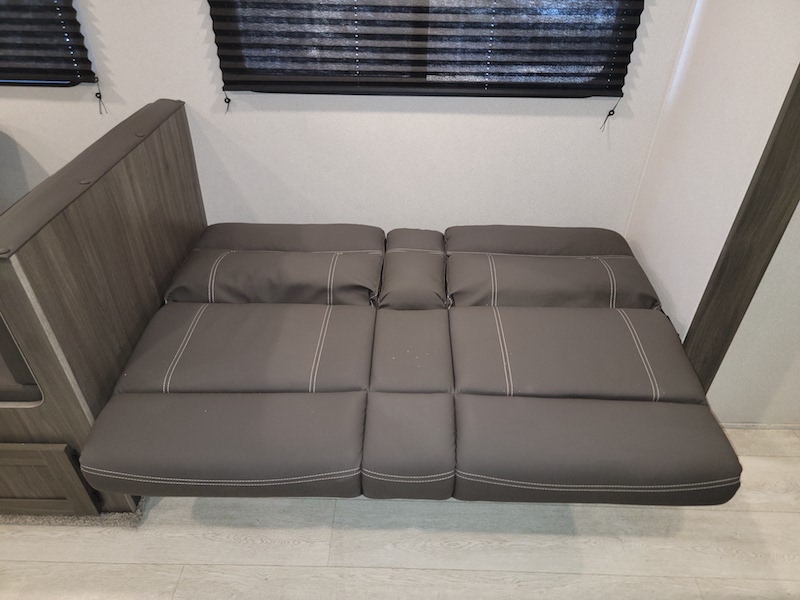 RV rental interior: Folded gray sofa/dinette converts to a bed, showing the versatile seating.. Forest River Shasta 2021