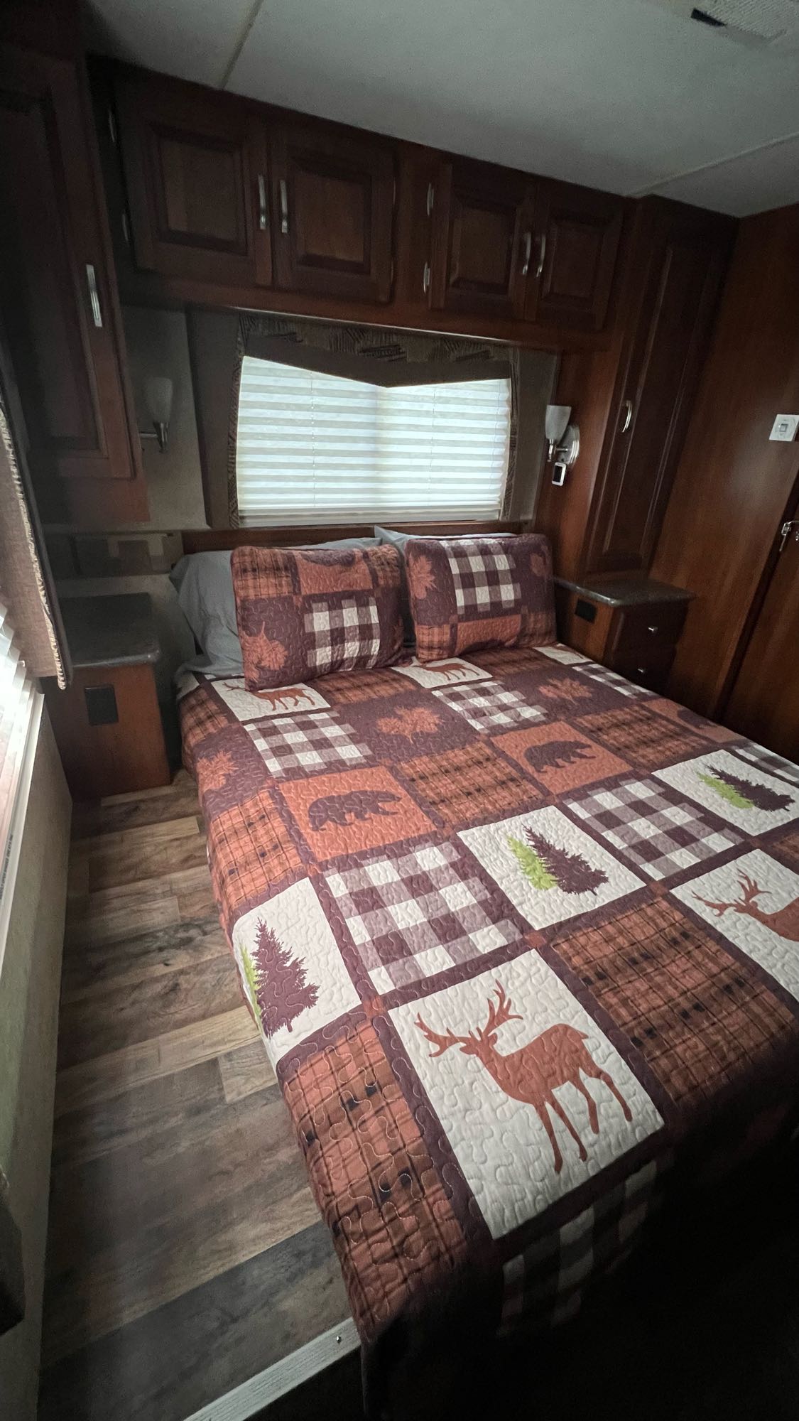 RV rental bedroom: Features a full bed with a rustic quilt, overhead storage, and wood-look flooring for a cozy stay.. Forest Rivers Georgetown 2013