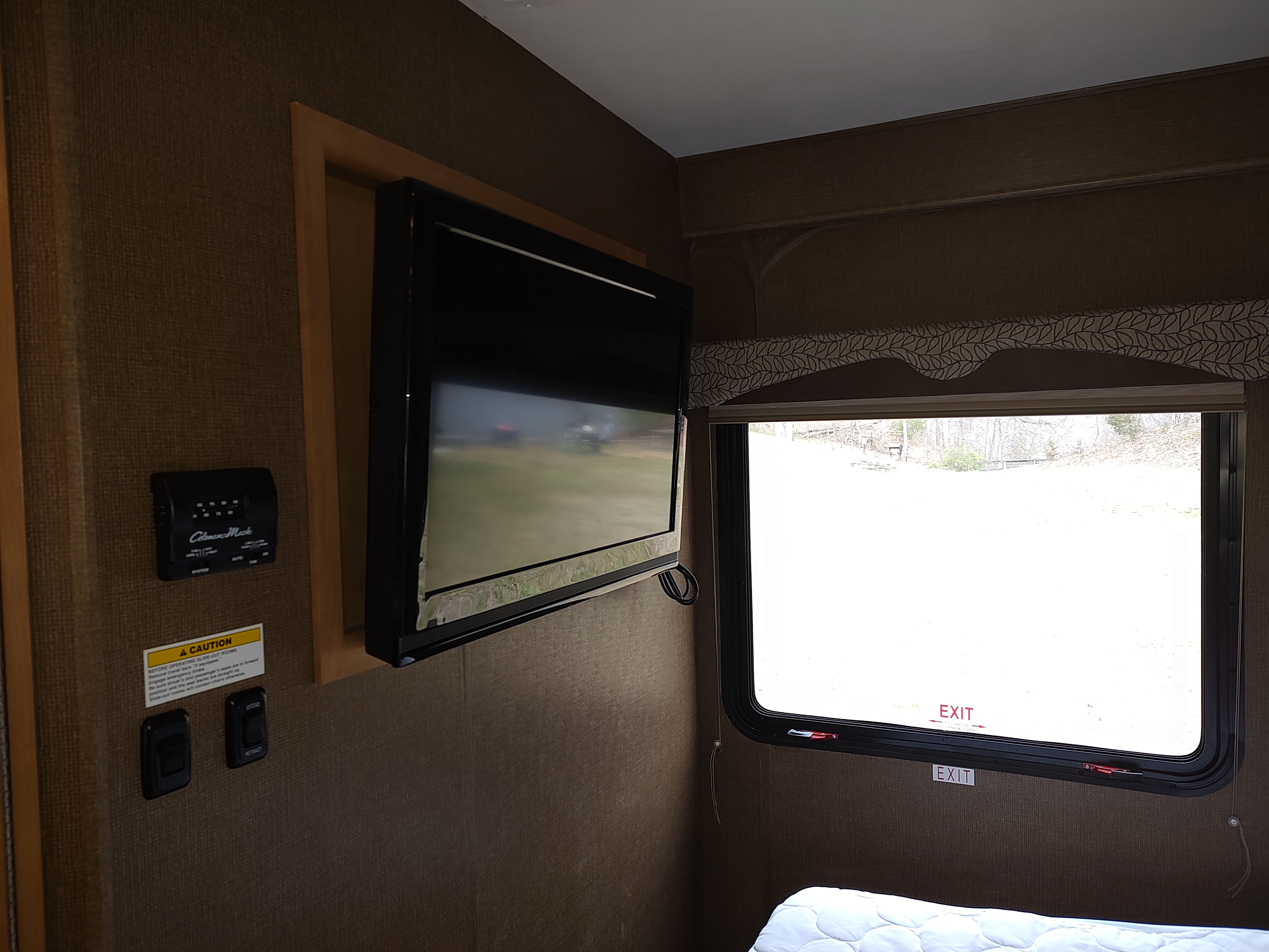 RV rental interior: TV, climate controls, and emergency exit window with outdoor view. Bed visible at bottom.. Thor Freedom Elite 2017