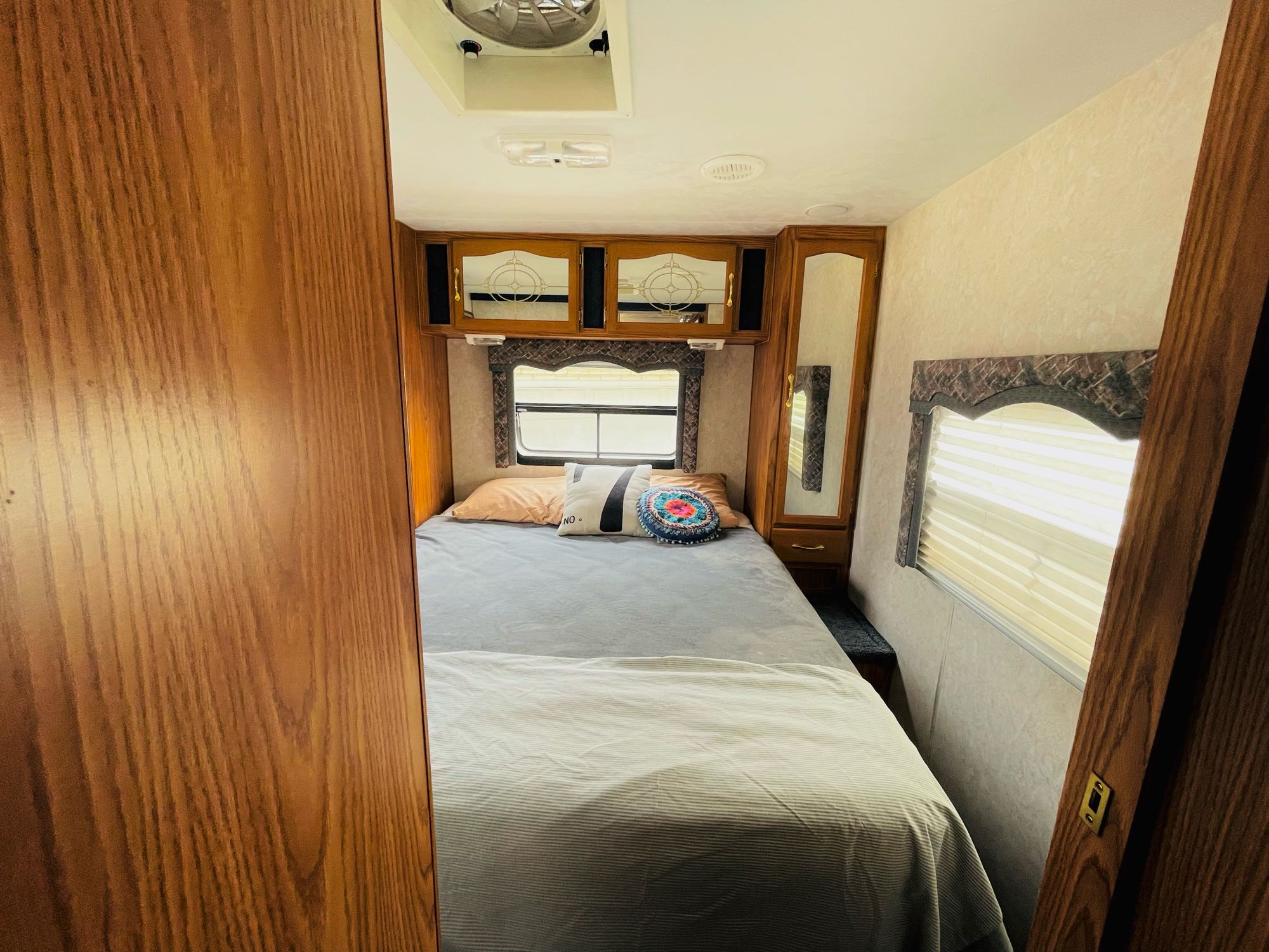 Comfortable RV rental bedroom with a cozy bed, overhead storage, and natural light from the window.. Komfort Komfort 2003