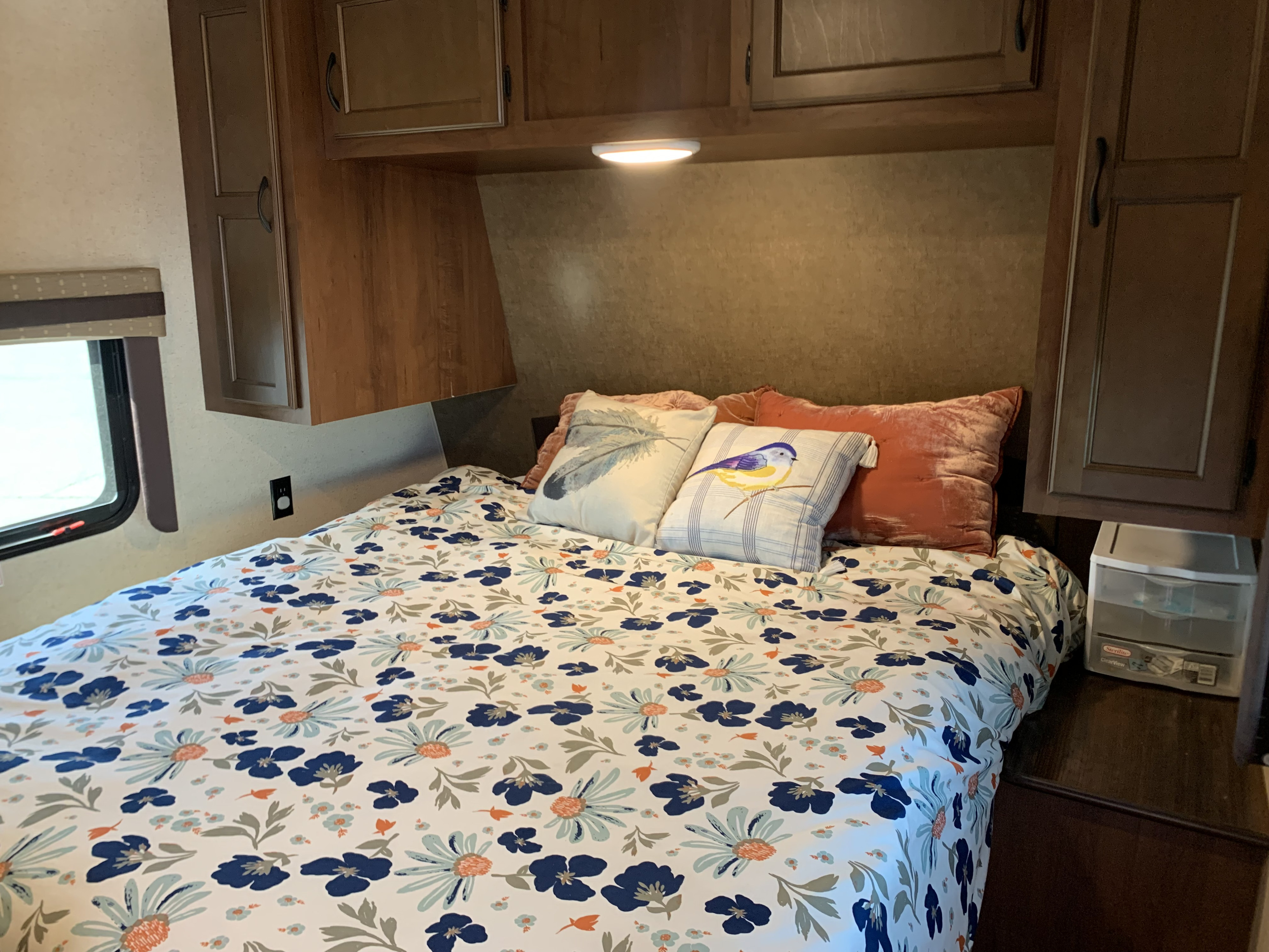 View inside a cozy RV bedroom, featuring a floral bedspread, storage cabinets, and a window, ideal for an rv rental.. Jayco Jay Flight 2015