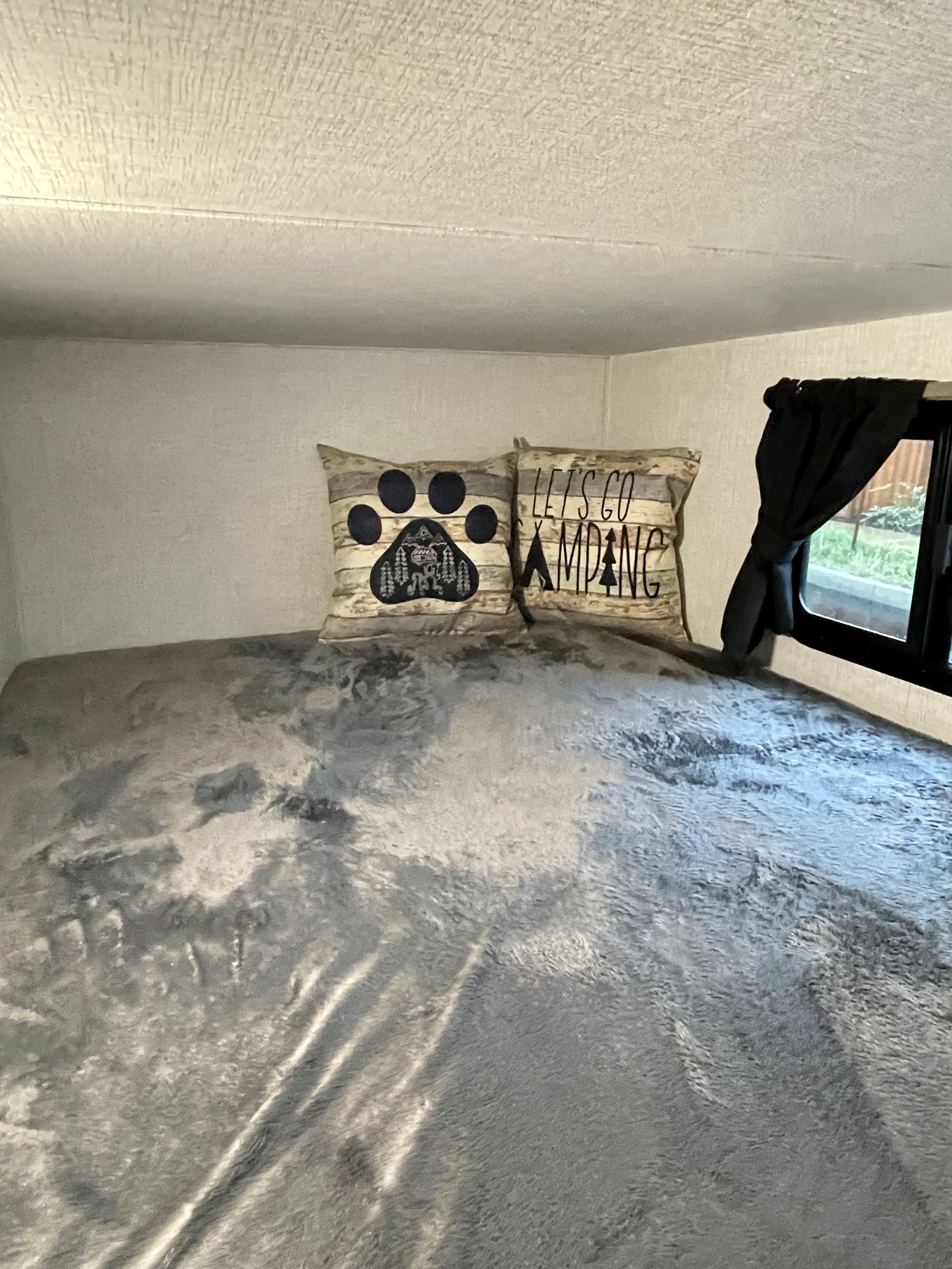Cozy RV rental bunk bed with "Let's Go Camping" pillows, soft gray blanket, and window view for a comfortable adventure.. Crossroads Sunset Trails 2022