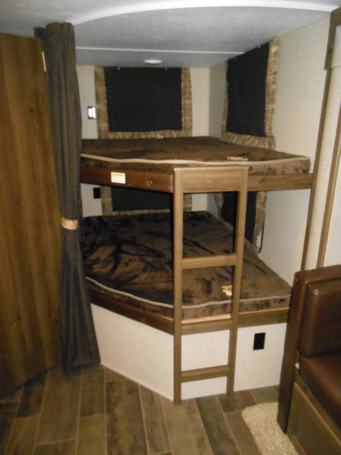Experience an RV rental: a compact interior with brown bunk beds and a wooden ladder.. Keystone RV Bullet Ultra Lite 2017