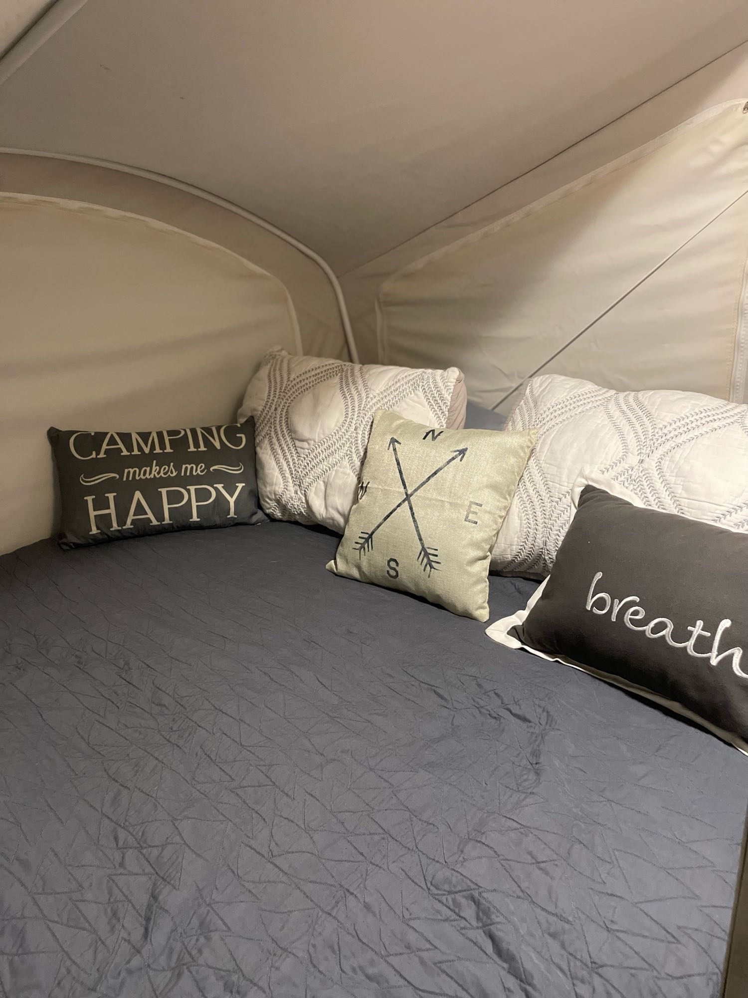 Cozy RV rental bed setup. Grey quilt & themed pillows (camping, compass, breathe) create a relaxing pop-up camper interior.. Coachmen CLIPPER 16RBD 2016