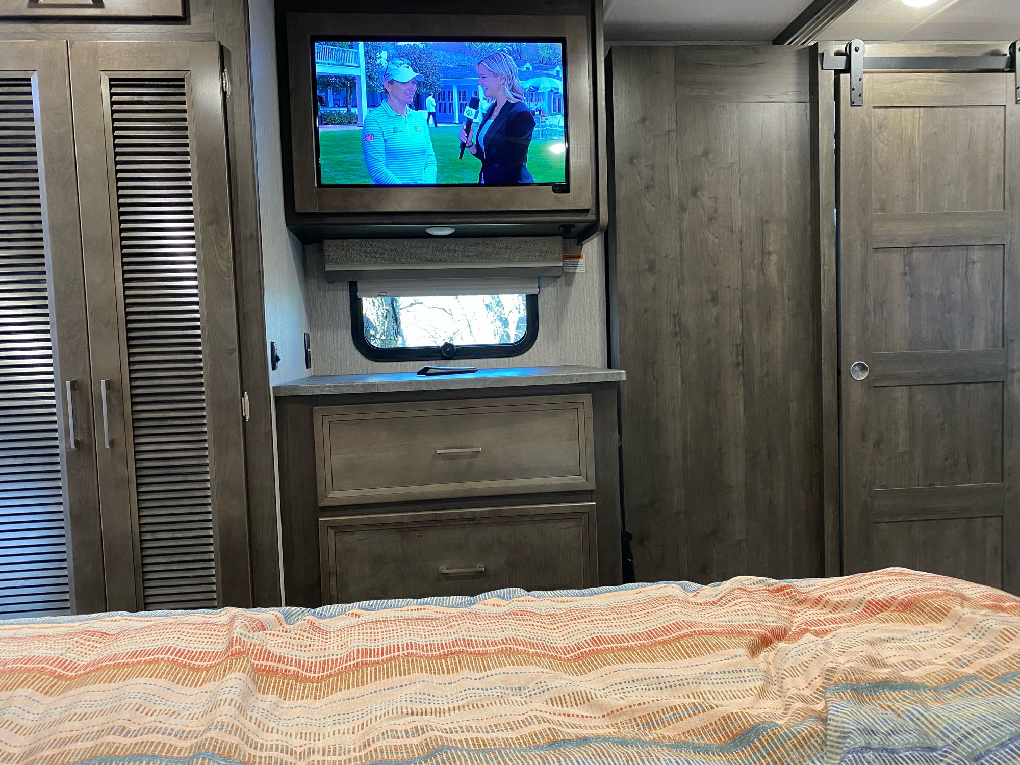 RV rental bedroom: TV over dresser, small window, louvered closets, and a stylish sliding barn door for your stay.. Forest River Coachmen Mirada 2022