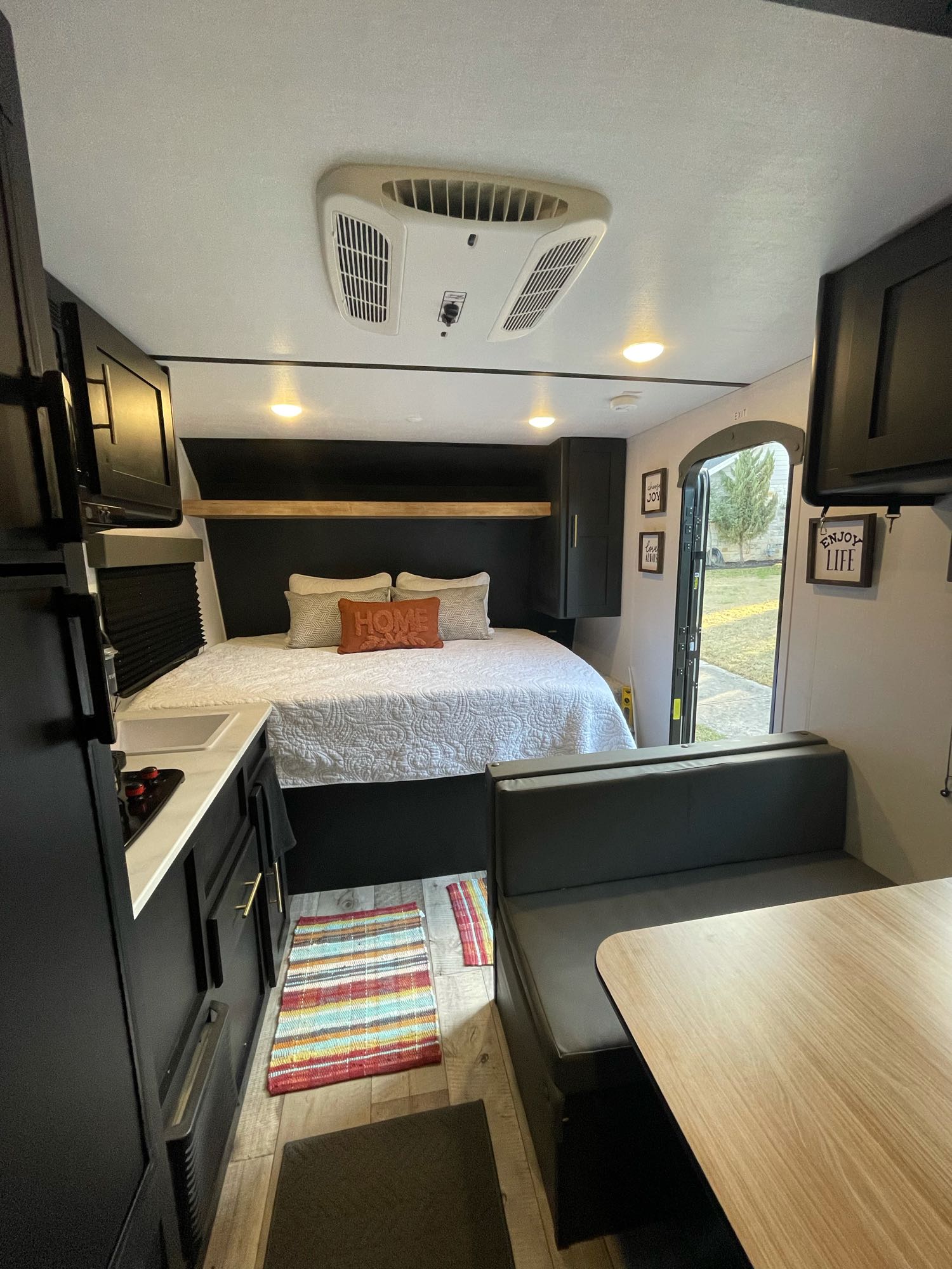 Cozy modern RV rental interior with bed, kitchen, and dining booth. Perfect for travel adventures!. Keystone Springdale 2022