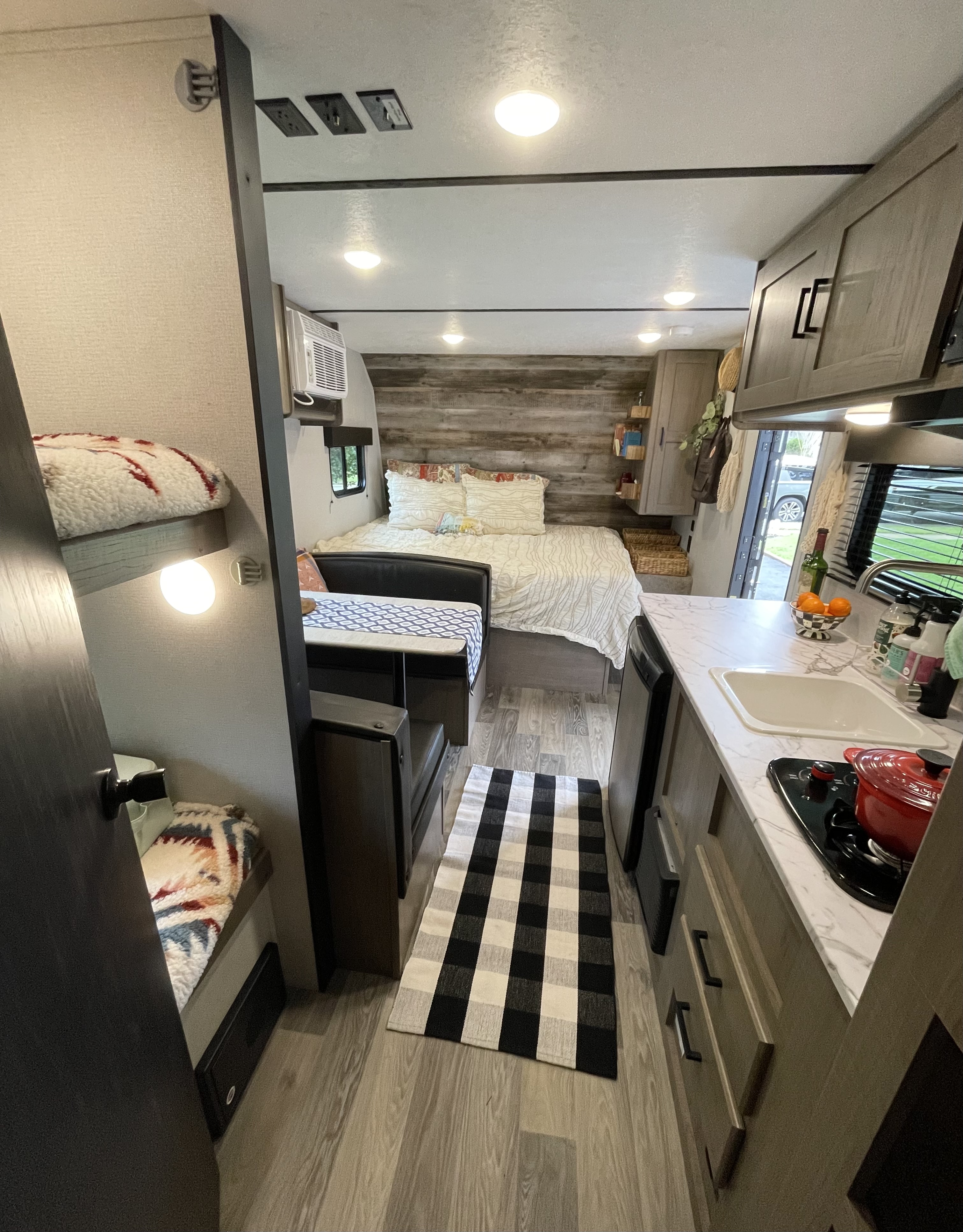 Step inside this RV rental: Features include a comfortable bed, dinette, full kitchen, bunk beds, and a cozy checkered rug.. Keystone RV Hideout LHS Mini 2021