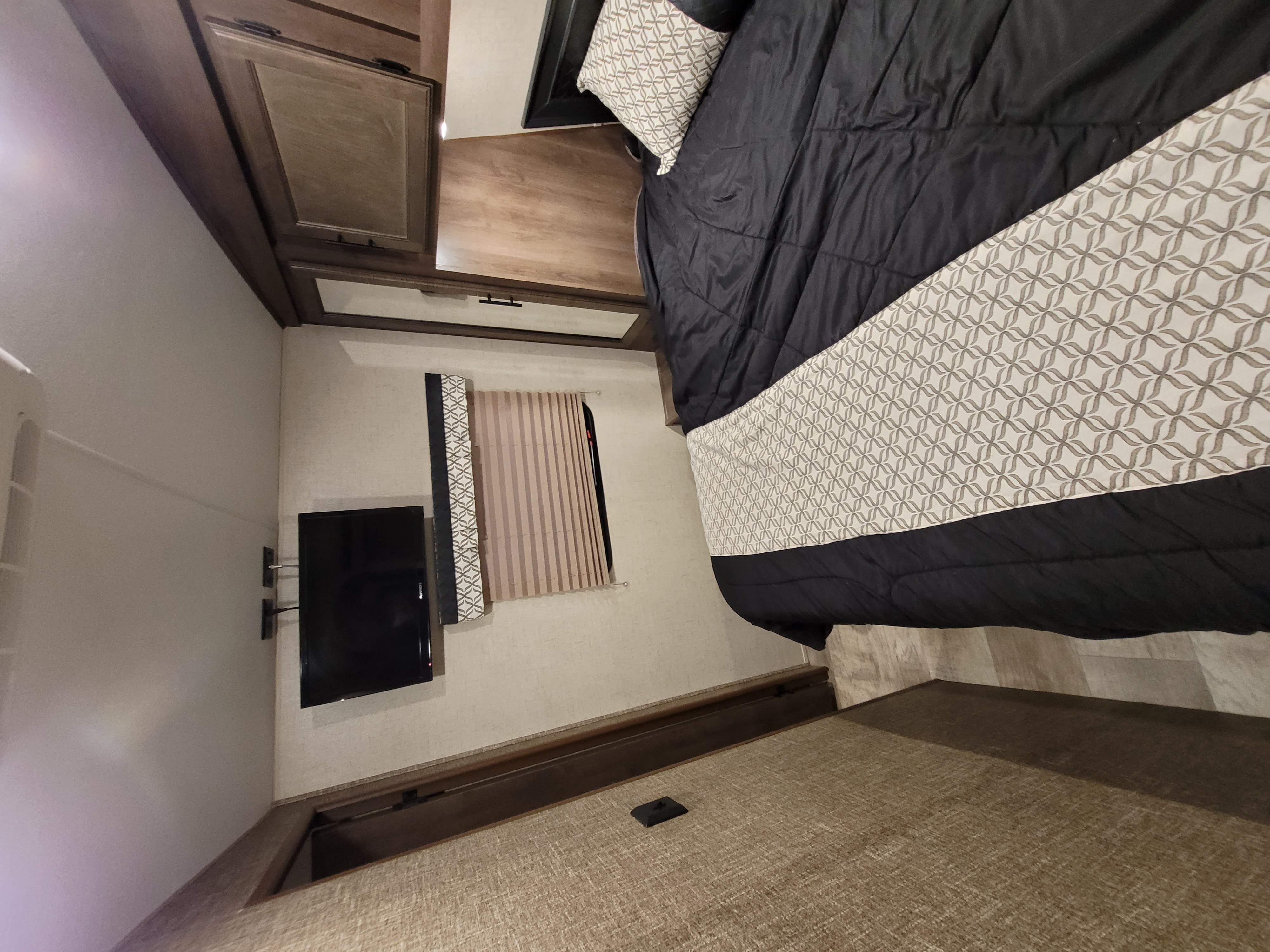 RV rental: Cozy RV bedroom with a bed, patterned bedding, wall-mounted TV, and overhead storage.. Spree Spree Trailer 2018