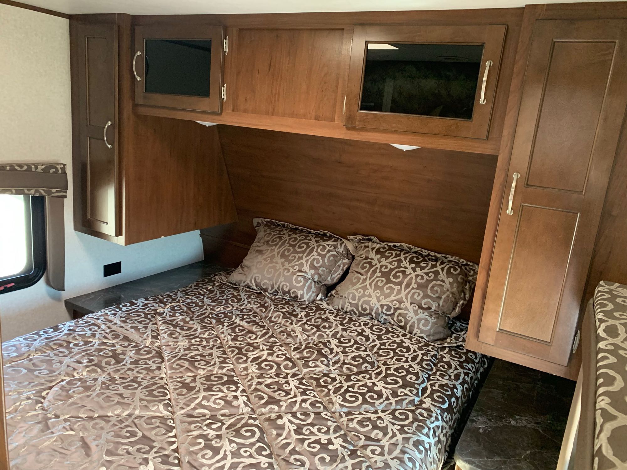 RV rental bedroom: a comfortable bed with patterned bedding, surrounded by warm wood cabinets and storage.. Jayco Jay Flight 2017