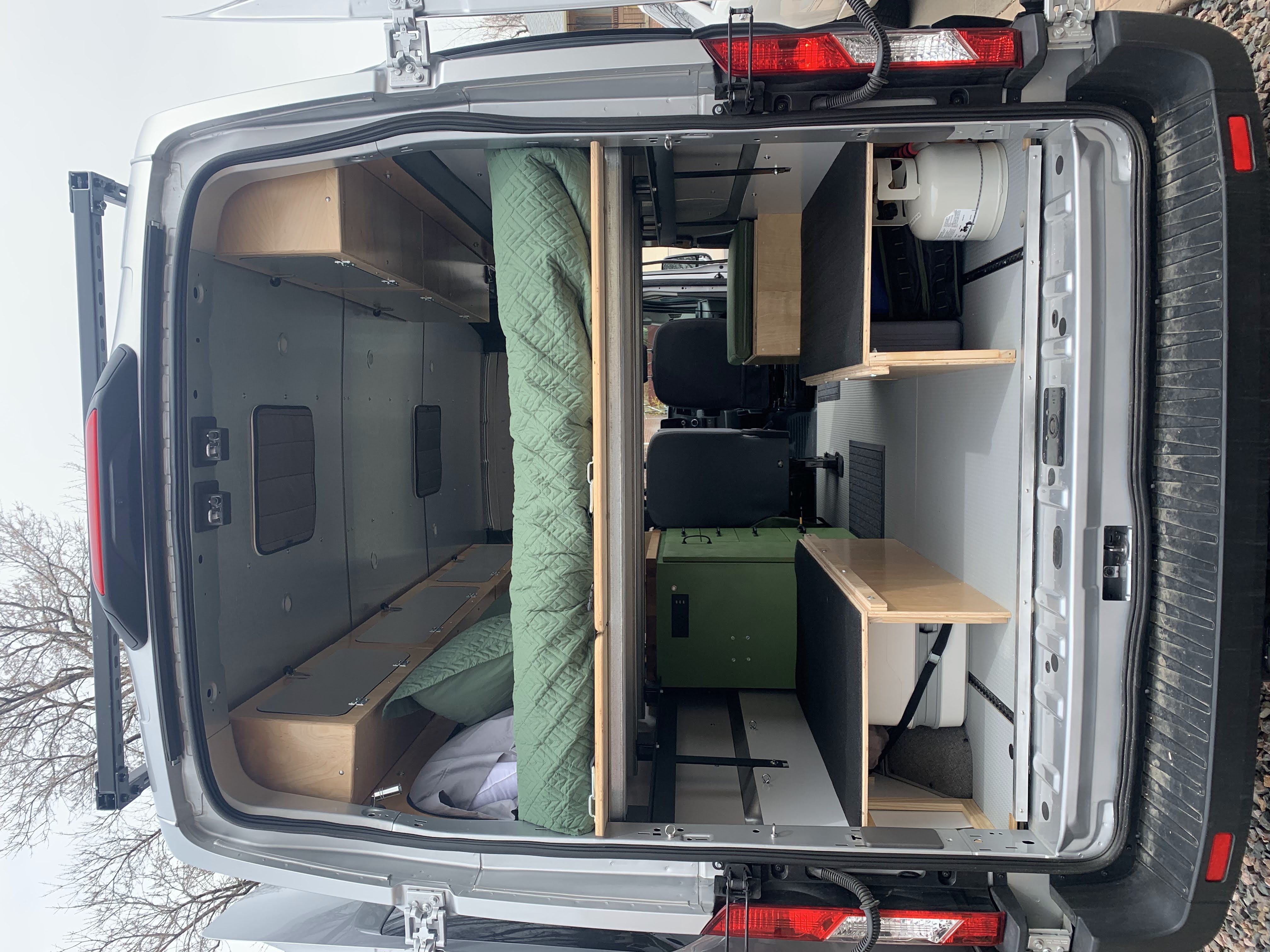 Inside a custom RV rental van, featuring a cozy sleeping area, ample storage, and functional living space for adventures.. Ford Transit 250 2021