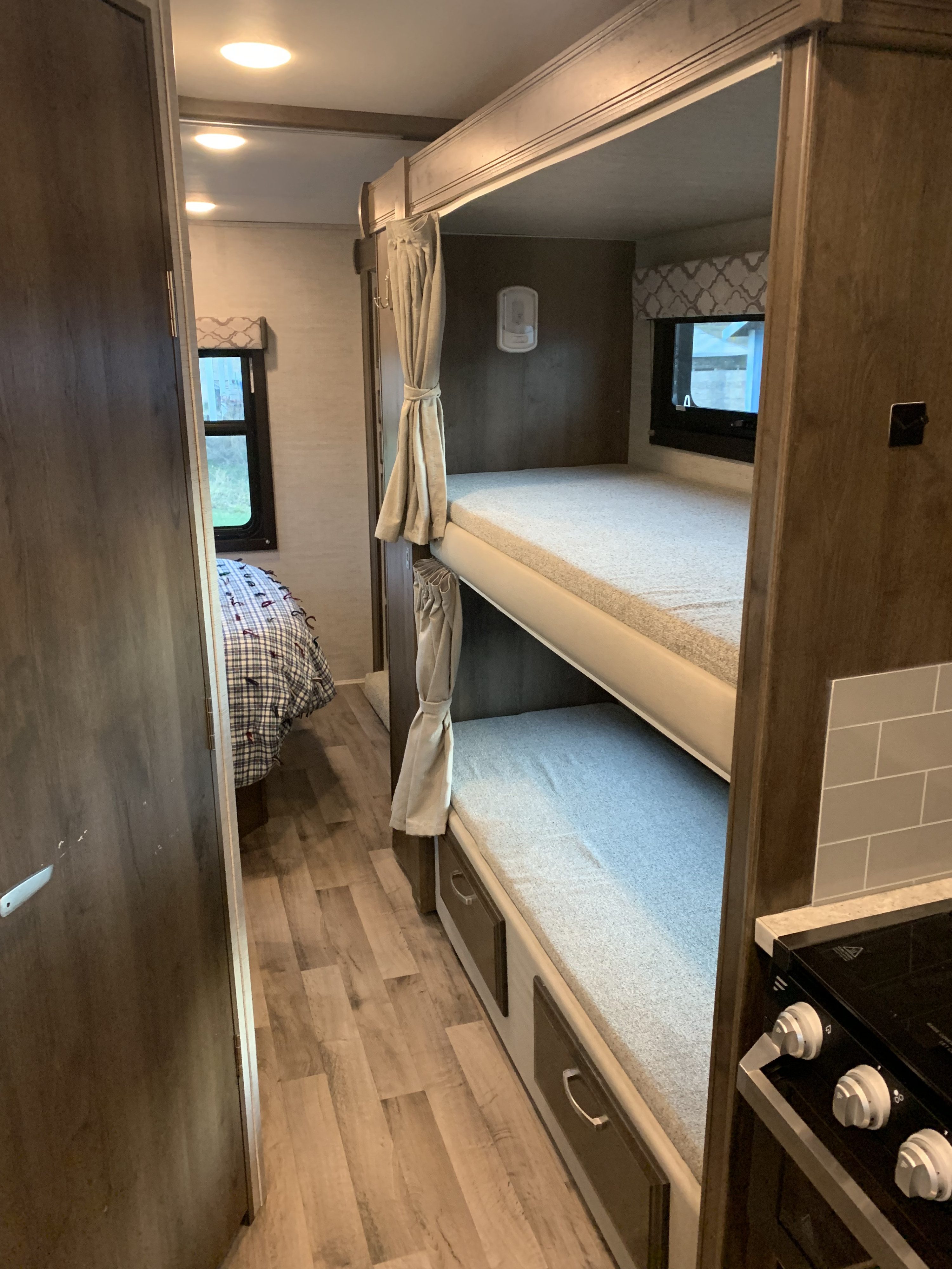 RV rental interior: bunk beds on the right, a bedroom visible at the end, and a kitchen area on the far right.. Jayco Redhawk 2021
