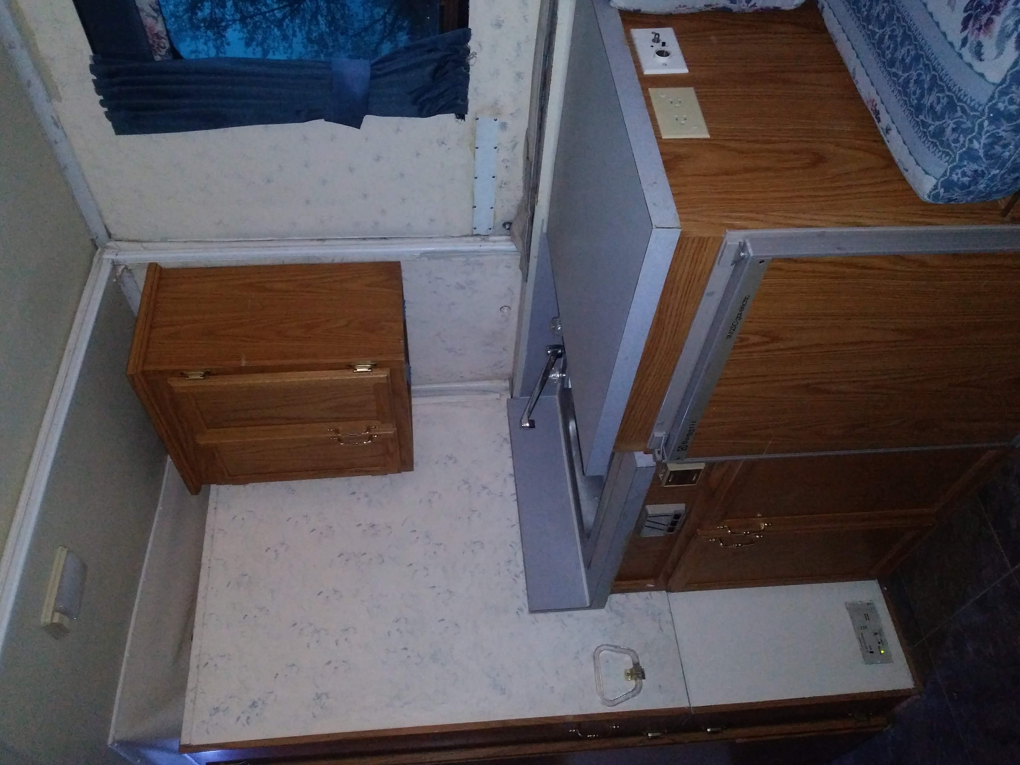 Inside an RV rental: a compact interior with wood cabinetry, fold-down sink, and sleeping/seating area.. Trailmanor 2619 1996