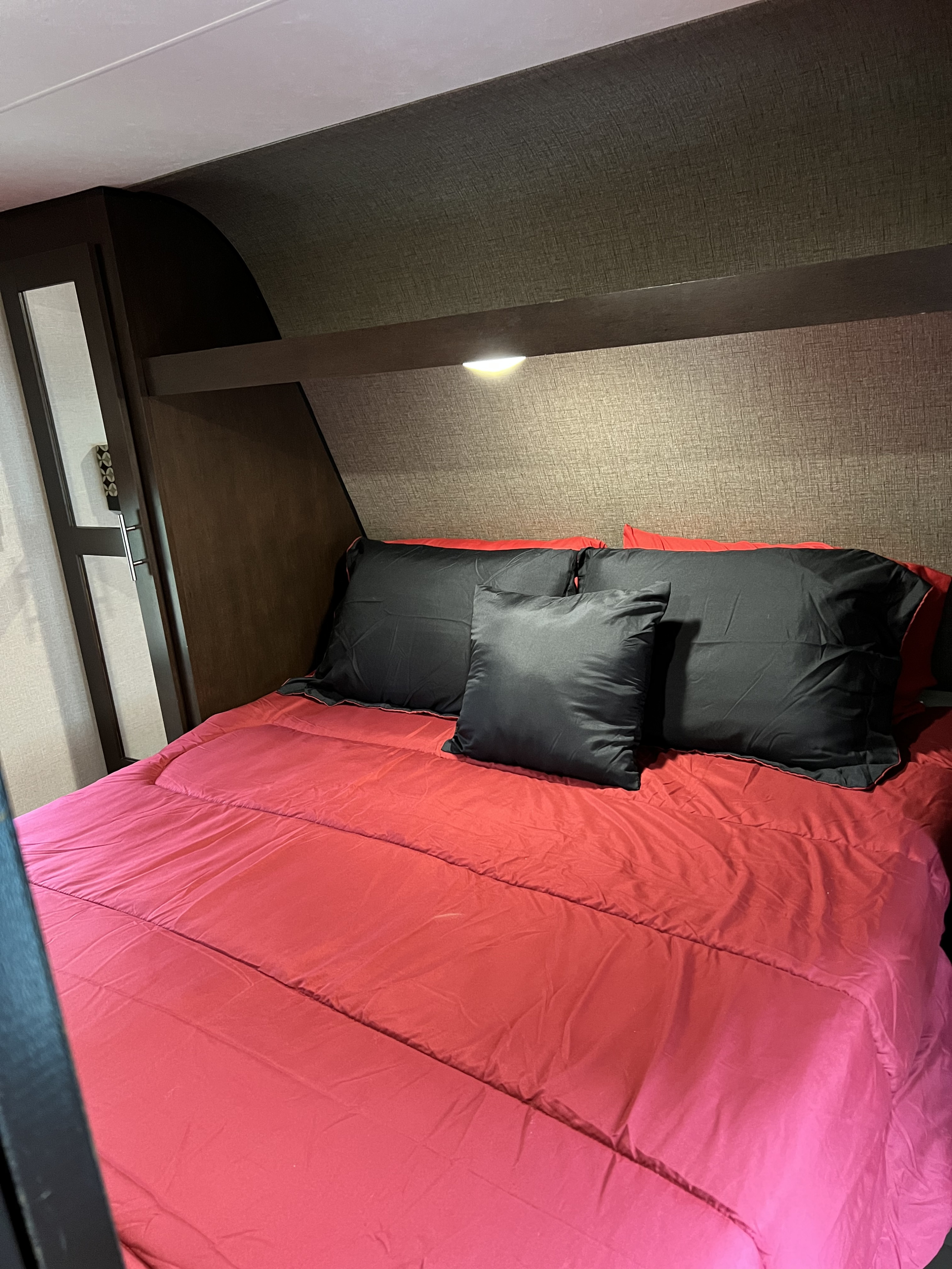 RV rental bedroom with red comforter, black pillows, and built-in lighting.. KZ Sportsmen 2018
