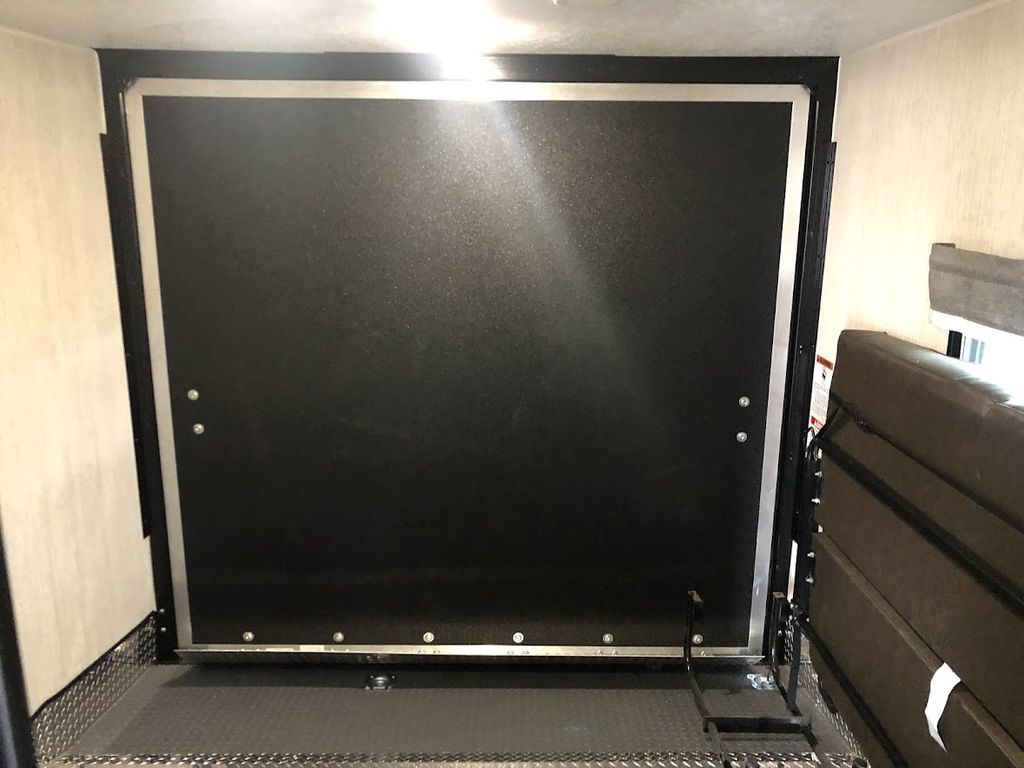 RV rental interior showcasing a toy hauler's utility garage, featuring a black rear ramp and folded sofa.. Palomino Puma Unleashed 2021