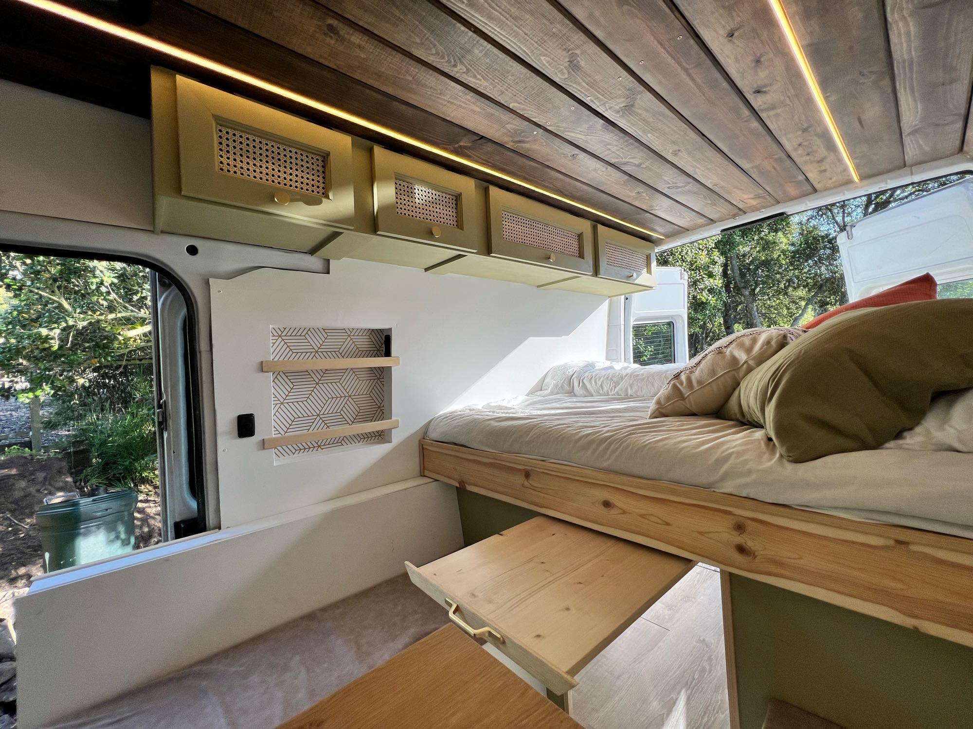 Custom RV rental interior featuring a wooden ceiling, chic cabinets, and a cozy bed with pull-out table, perfect for mobile living.. Mercedes-Benz Sprinter 2006