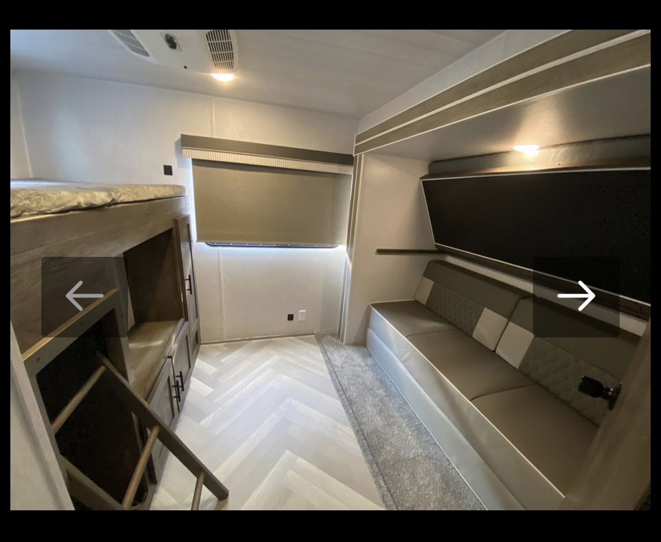 Modern RV rental bunkhouse interior featuring comfortable bunk beds, storage, and a sofa.. Forest River 32BHDS 2022