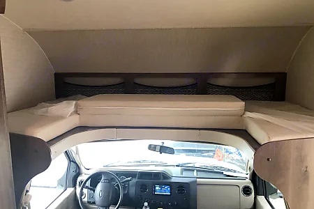 Inside an RV rental: a comfortable cab-over bunk rests above the driver's cockpit and dashboard.. Jayco Redhawk 2018