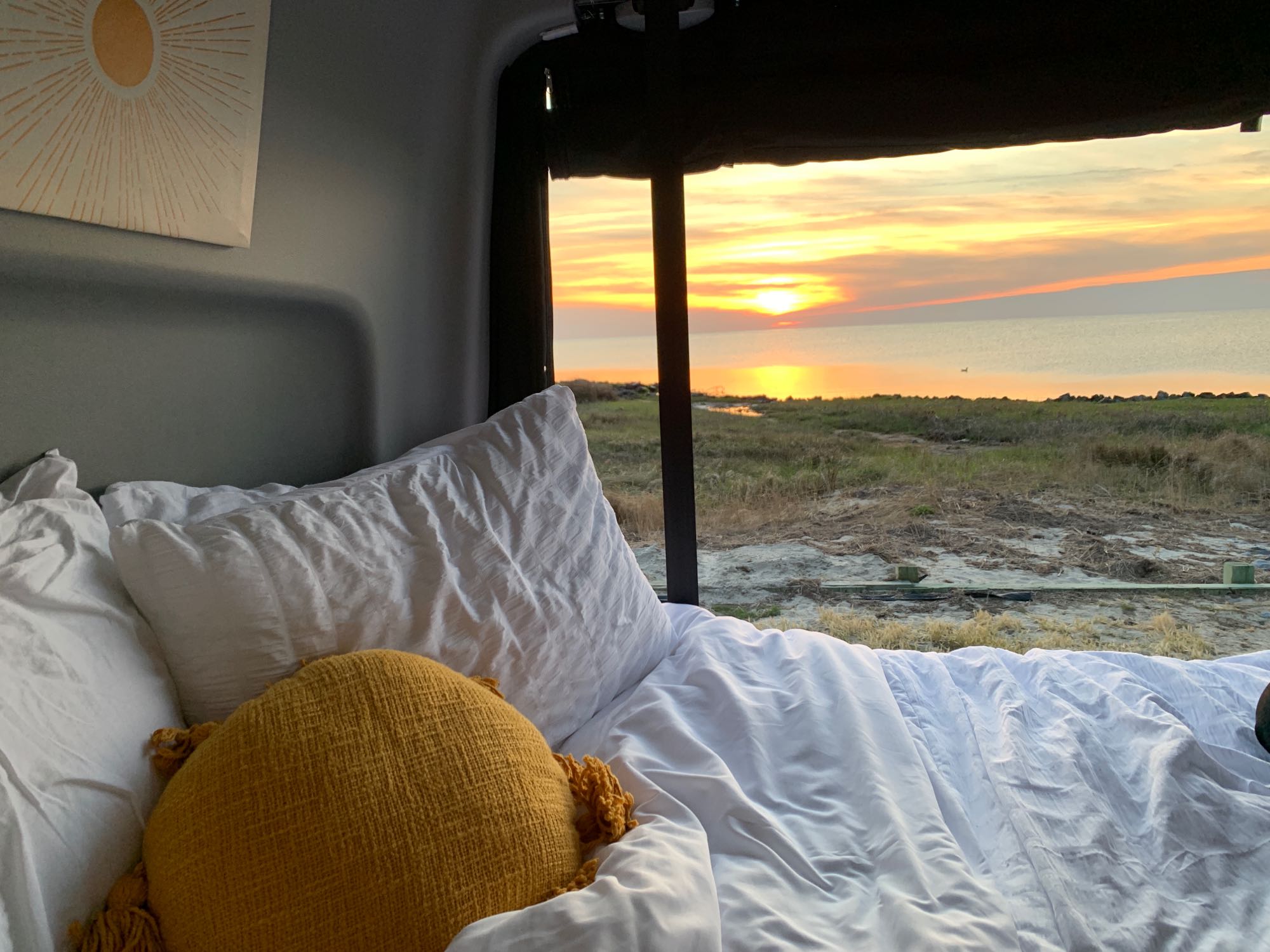 Relaxing RV rental bedroom with stunning sunset view over water. Perfect for a comfortable travel escape.. Winnebago Revel 2022