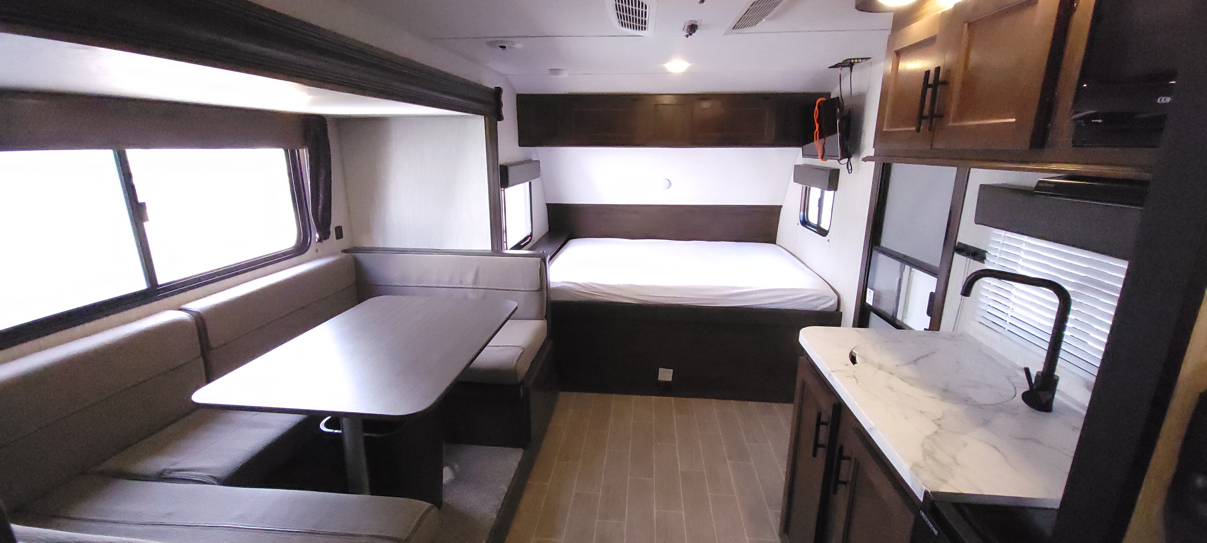 This RV rental interior features a cozy dinette, comfortable bed area, and a compact kitchen counter with a sink, all in one view.. Forest River Wolf Pup 2020