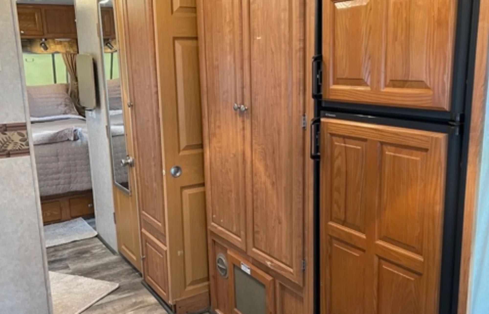 RV rental interior showing a wood-paneled hallway with cabinetry, refrigerator, and a glimpse of the bedroom.. Forest River Rockwood Ultra Lite 2009