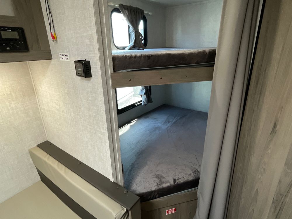 Inside an RV rental: two bunk beds, dinette, and control panel. Ideal for family camping.. Gulfstream Enlighten 19BH 2022