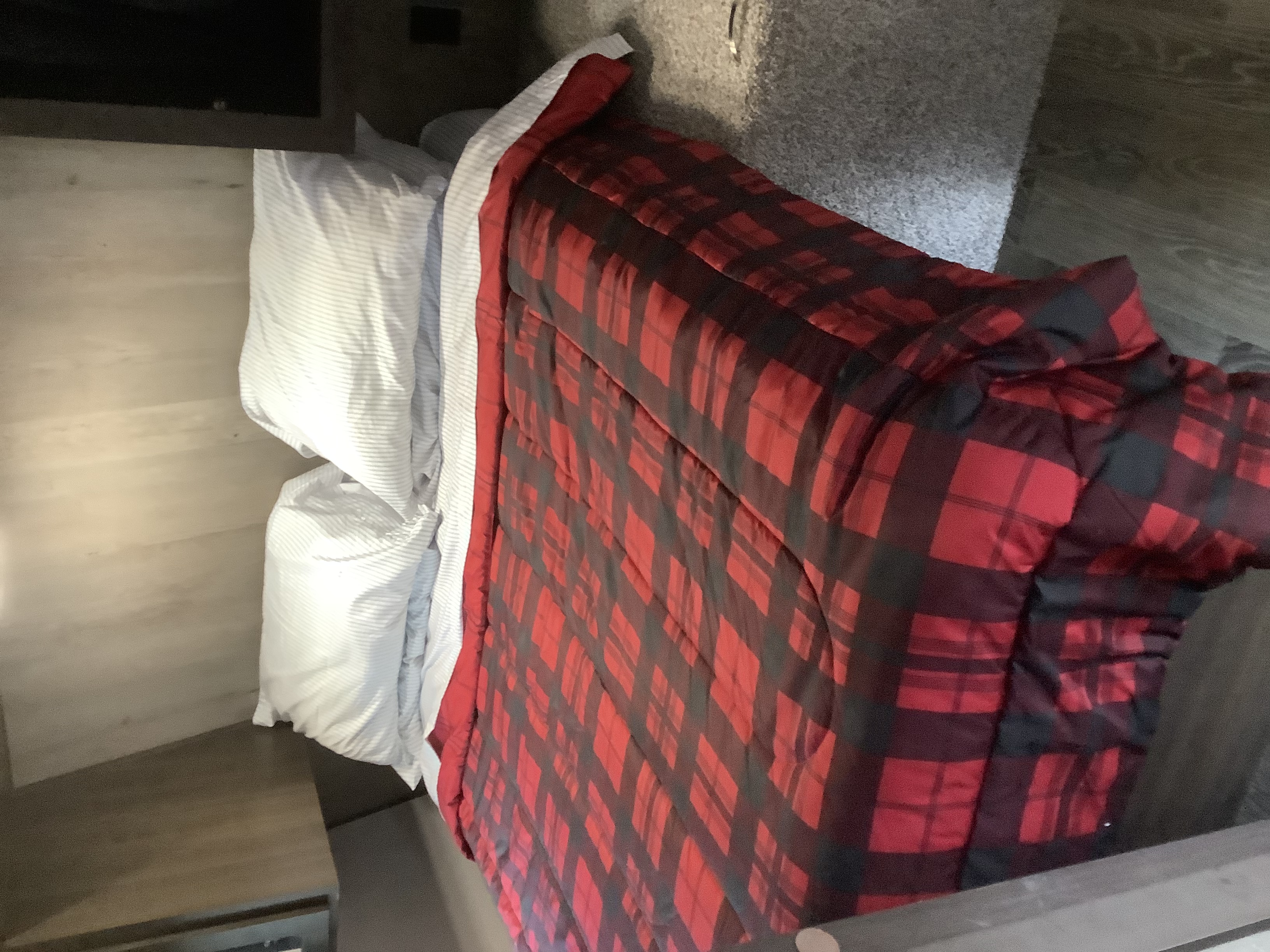 Cozy RV rental bed featuring a red and black plaid comforter and striped pillows, perfect for a comfortable travel stay.. Other Other 2020