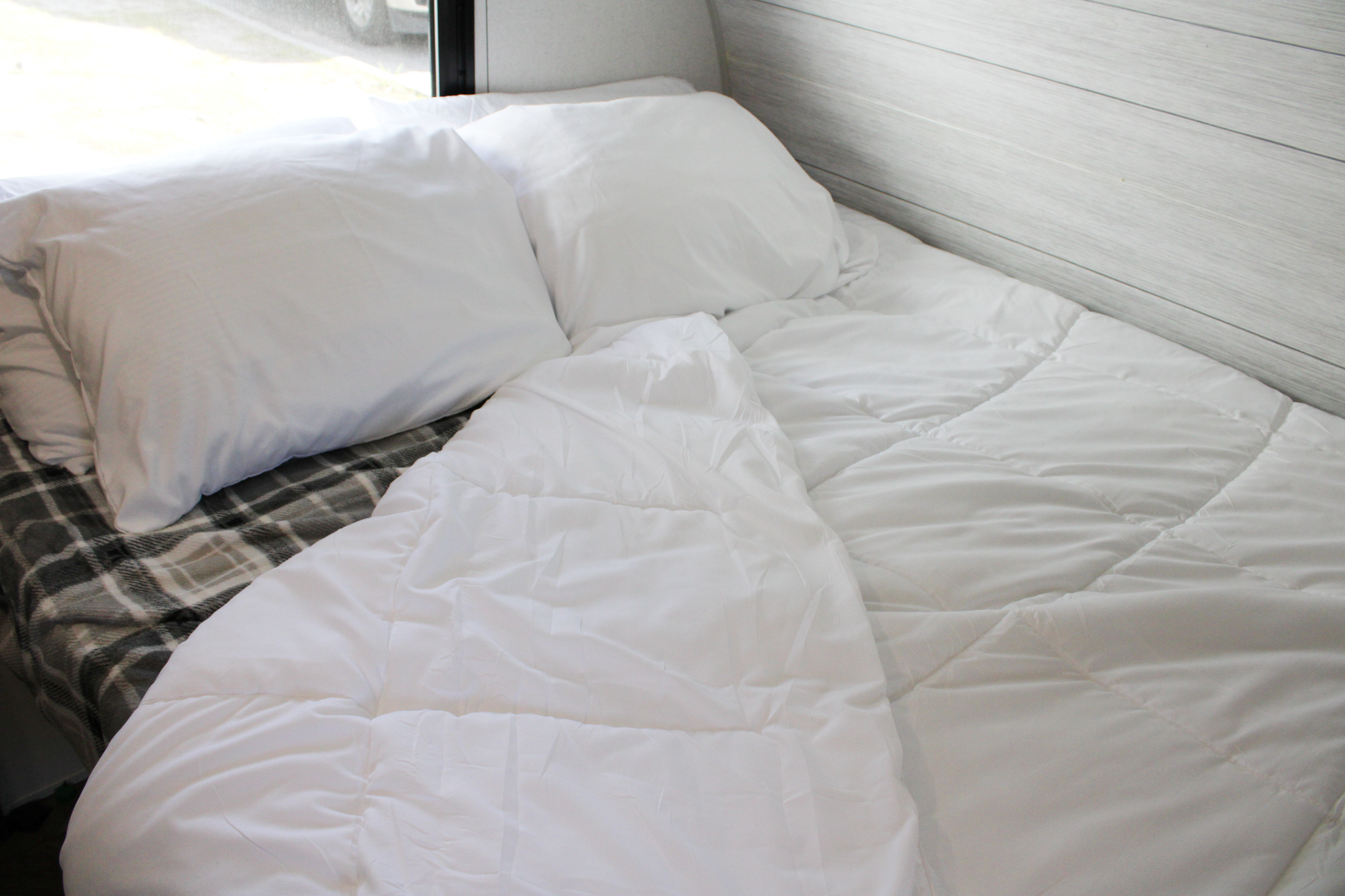 Cozy RV rental bed with white linens & pillows over a plaid blanket; perfect for a restful sleep.. Forest River Salem FSX 2021