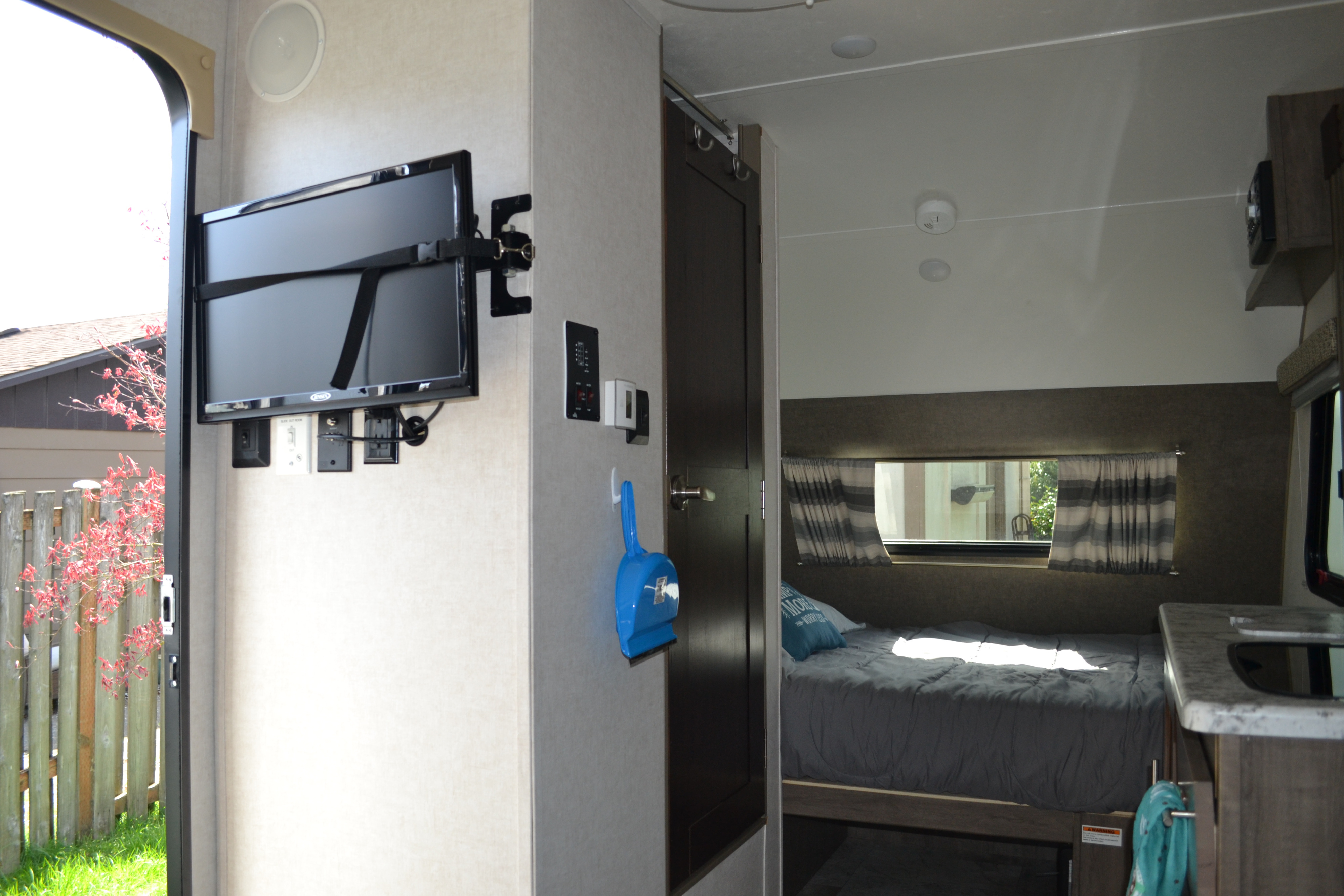 This RV rental interior features a compact living space with a mounted TV, a cozy bedroom, and a partial kitchen.. R-Pod R177 2018