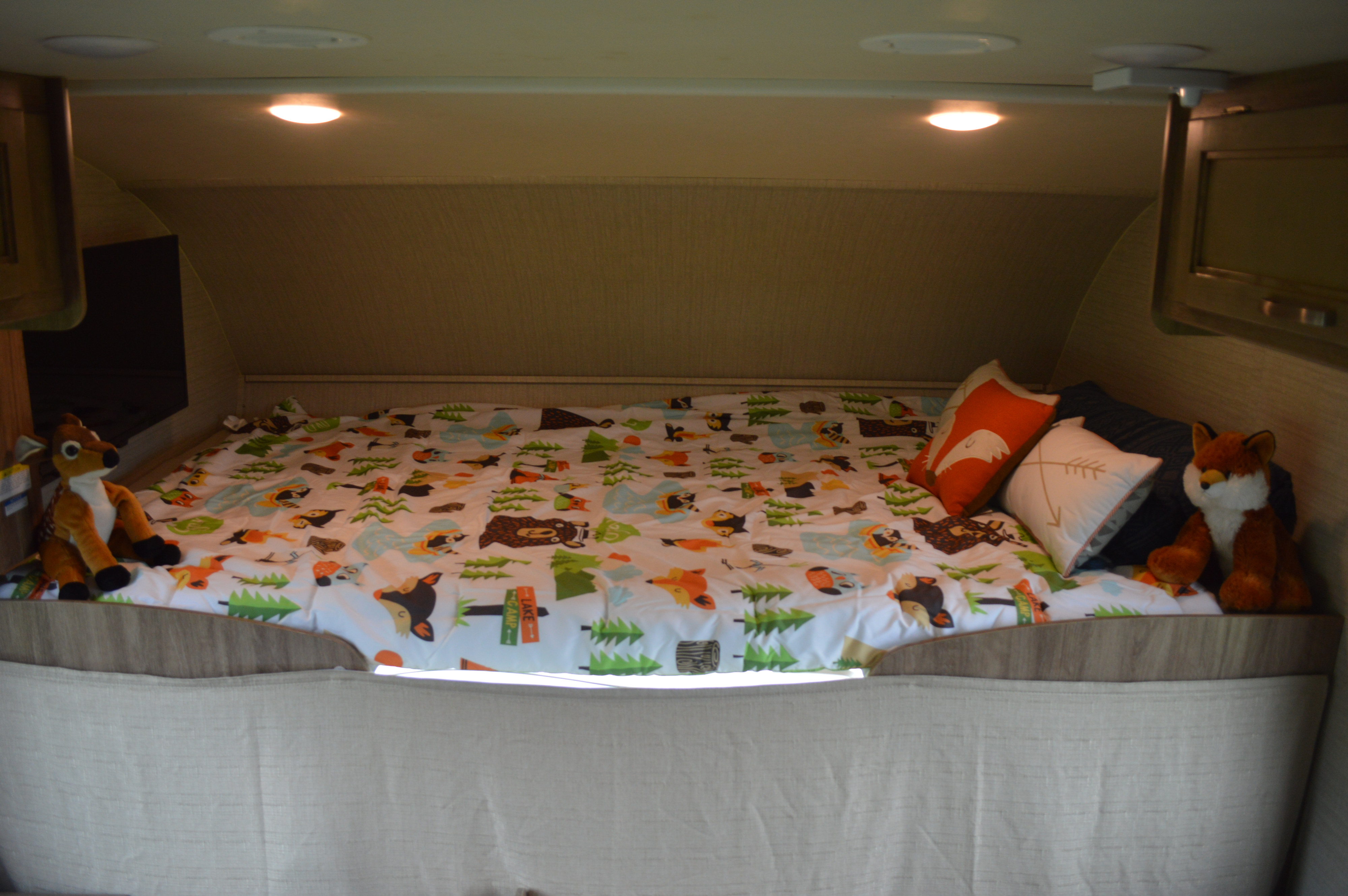 Cozy RV rental bed with woodland theme, featuring animal bedding and stuffed toys.. Jayco Redhawk SE 2020