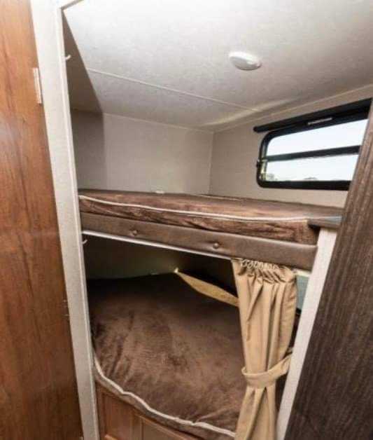 RV rental interior showing bunk beds. The lower bunk has a privacy curtain, and a window is visible.. Coachmen Other 2018