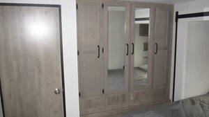 Spacious RV rental bedroom with integrated wardrobe featuring mirrored doors and light wood finishes for optimal storage.. Palomino Puma 2021