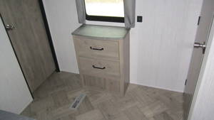 RV rental bedroom detail: light wood dresser, window, and patterned flooring offering convenient storage.. Palomino Puma 2021