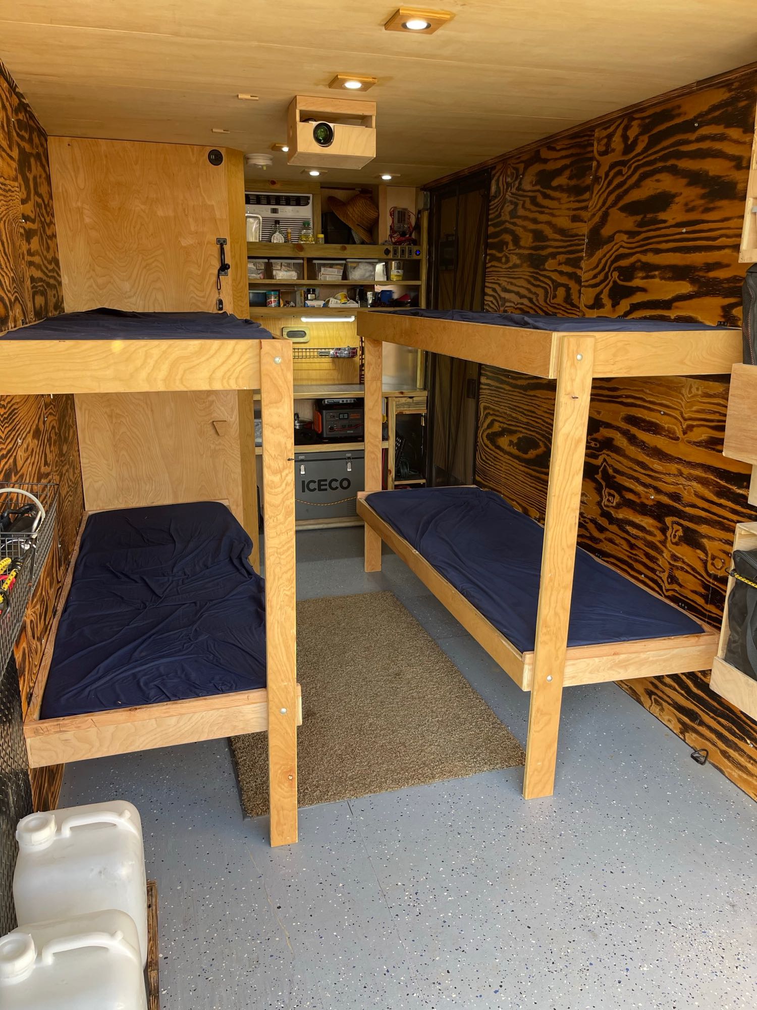 This RV rental offers a functional trailer interior featuring two sets of bunk beds and a compact kitchen/storage area.. Custom Camper 2019