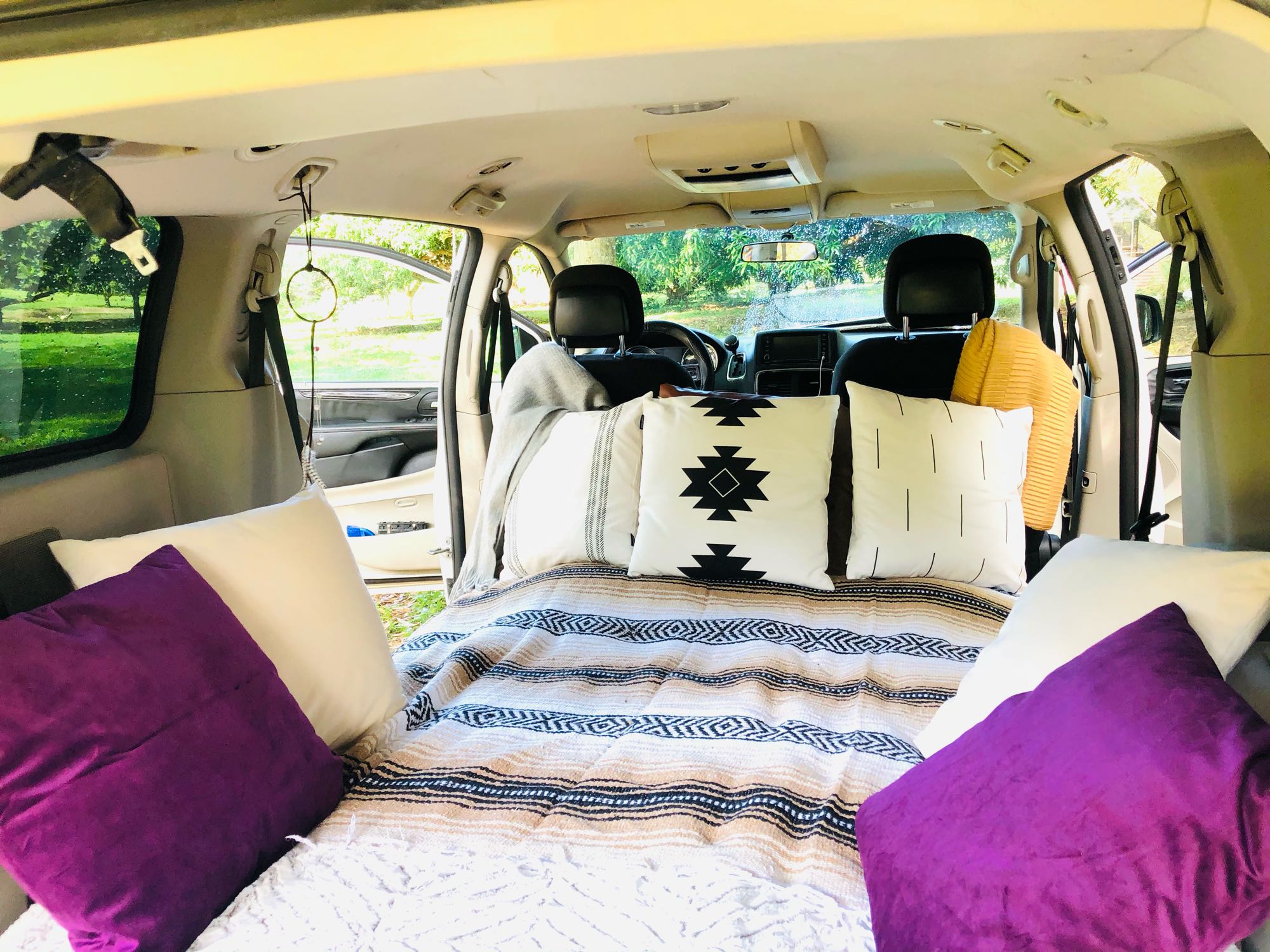 Cozy interior of an RV rental, featuring a comfortable bed with decorative pillows & striped blankets, ideal for car camping.. Dodge Other 2013