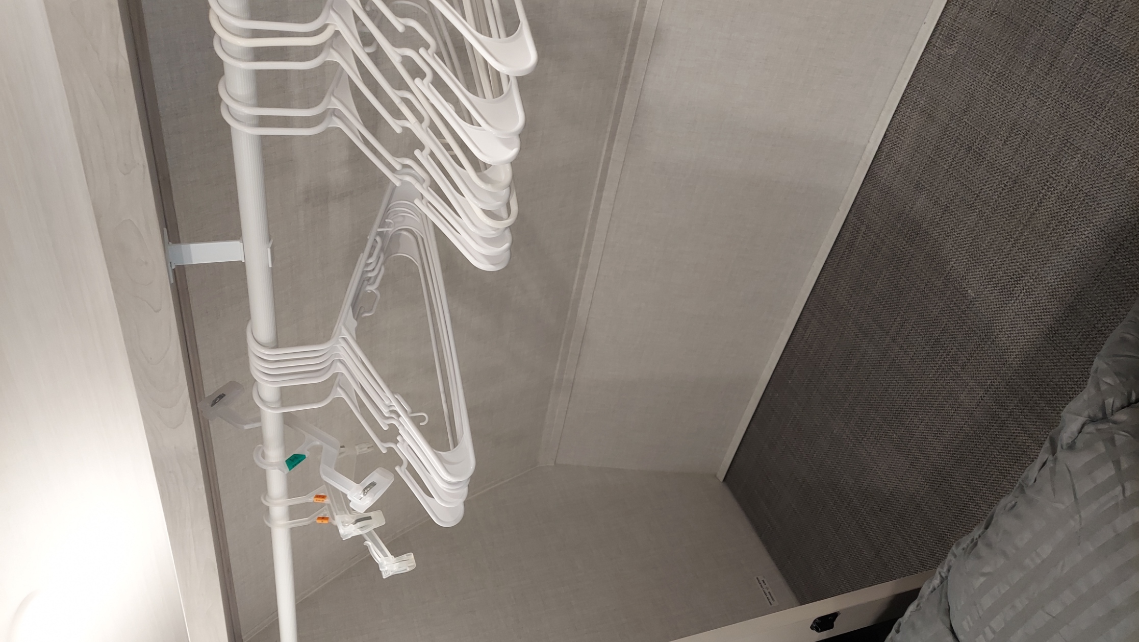 RV rental interior: A white hanging rod with many white plastic hangers in a compact closet offers travel storage.. East to West Tandara 2021