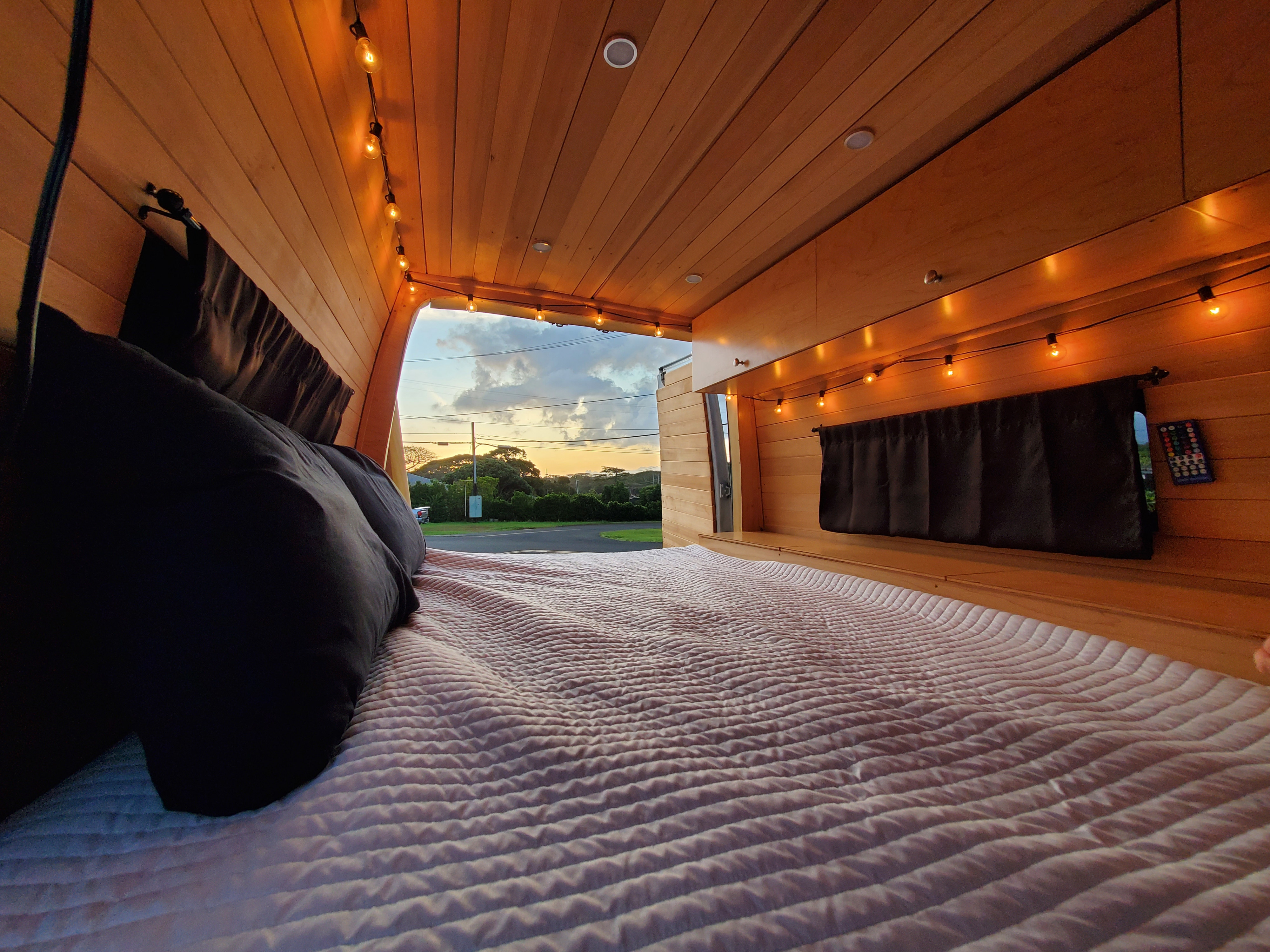 Cozy RV rental interior with a comfy bed, warm string lights, and a beautiful sunset view from the back.. Mercedes-Benz Sprinter 2007
