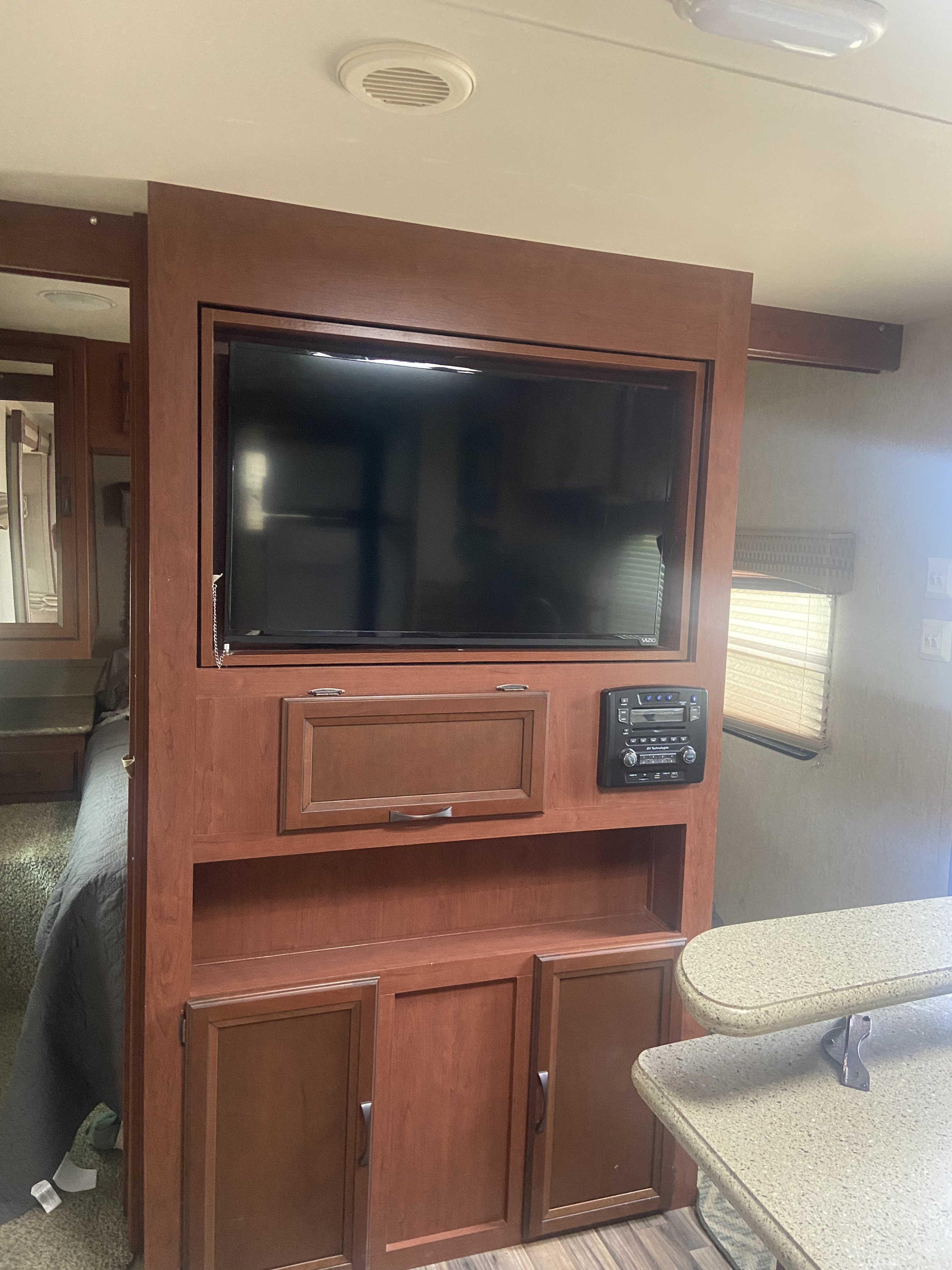 Inside this RV rental: a large wooden entertainment center with TV, stereo, and ample storage, separating the living area from the bedroom.. Palomino Puma 2015