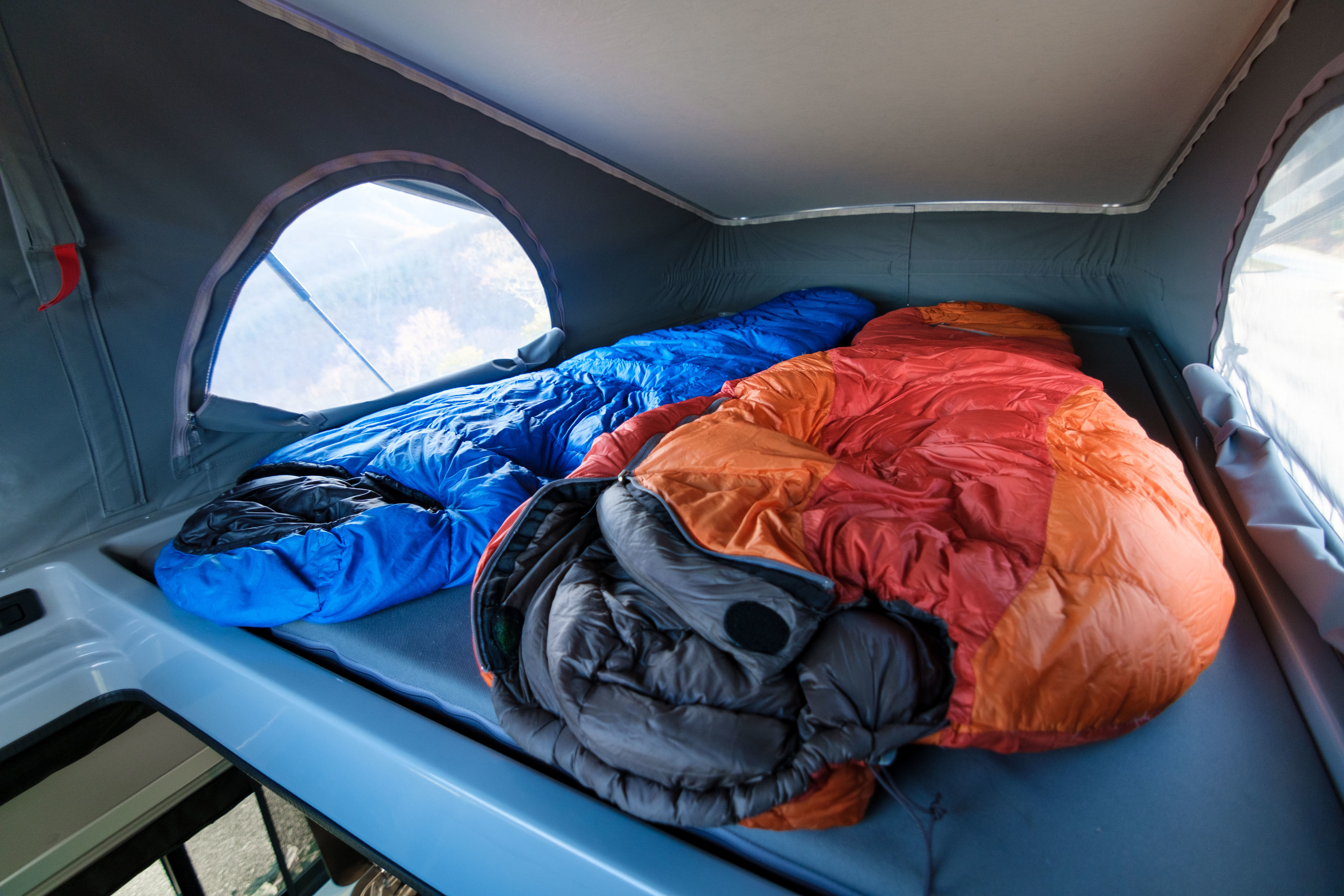 Inside a pop-top rv rental, two colorful sleeping bags await. A comfortable camping bed for outdoor adventures.. Winnebago Solis 2022