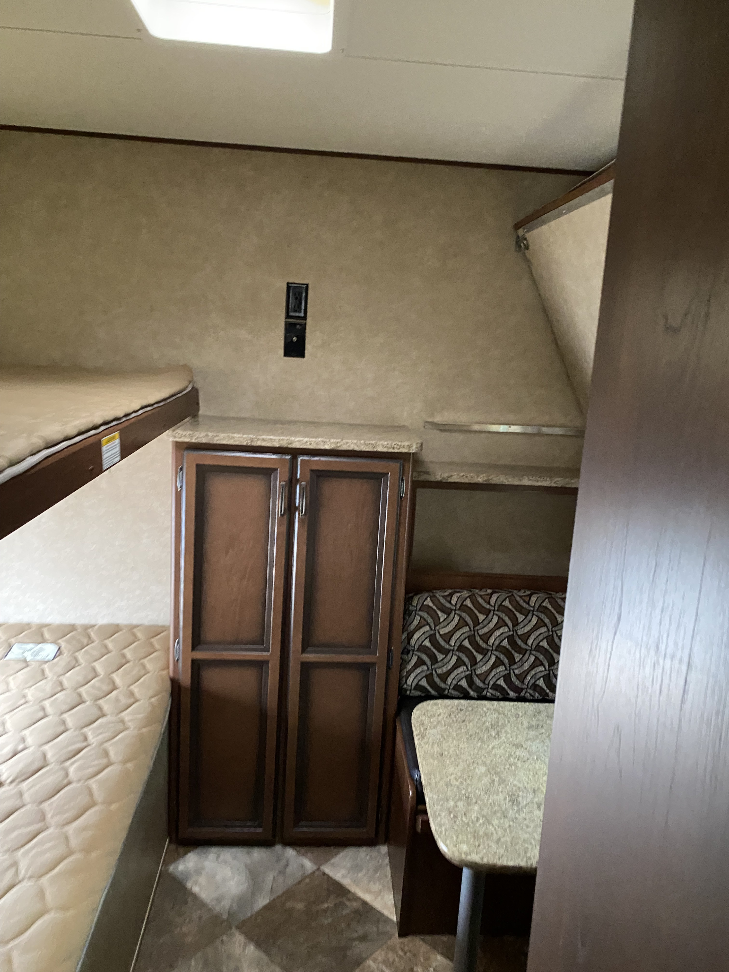 Inside this RV rental: bunk beds, wood cabinets, and a dinette with patterned cushions. Perfect for compact living on the road.. Crossroads RV Zinger 2015