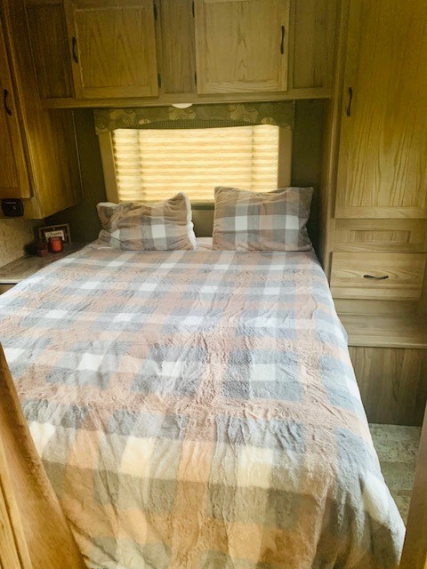 Comfortable RV rental bedroom with plaid bedding, window, and ample storage.. Forest River Coachmen Freelander 2016