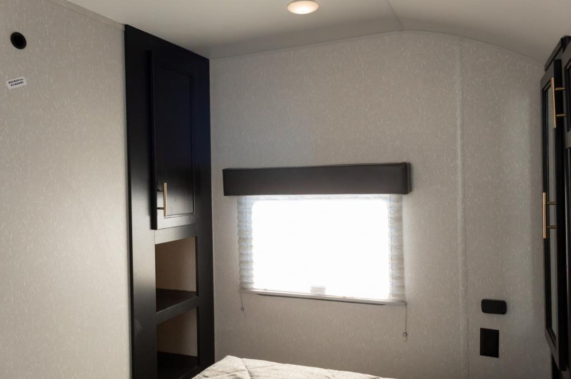 Cozy RV rental bedroom with dark storage cabinets, a bright window, and bed. Perfect for travel trailer adventures.. Forest River 271brb 2022
