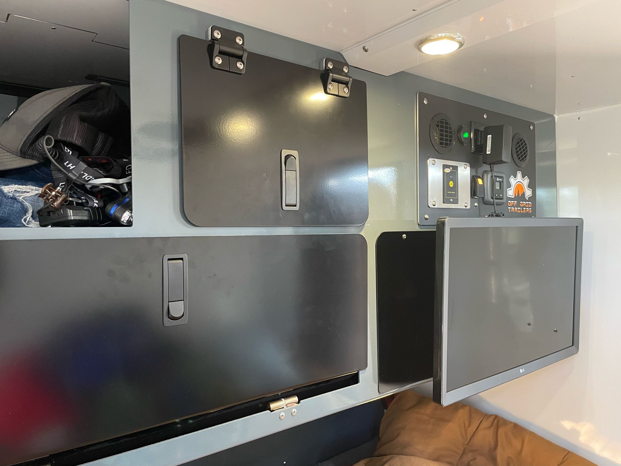 Inside an RV rental: organized storage, essential control panel, and entertainment monitor for off-grid adventures.. Off-Grid Trailers Pando 2.0 2022
