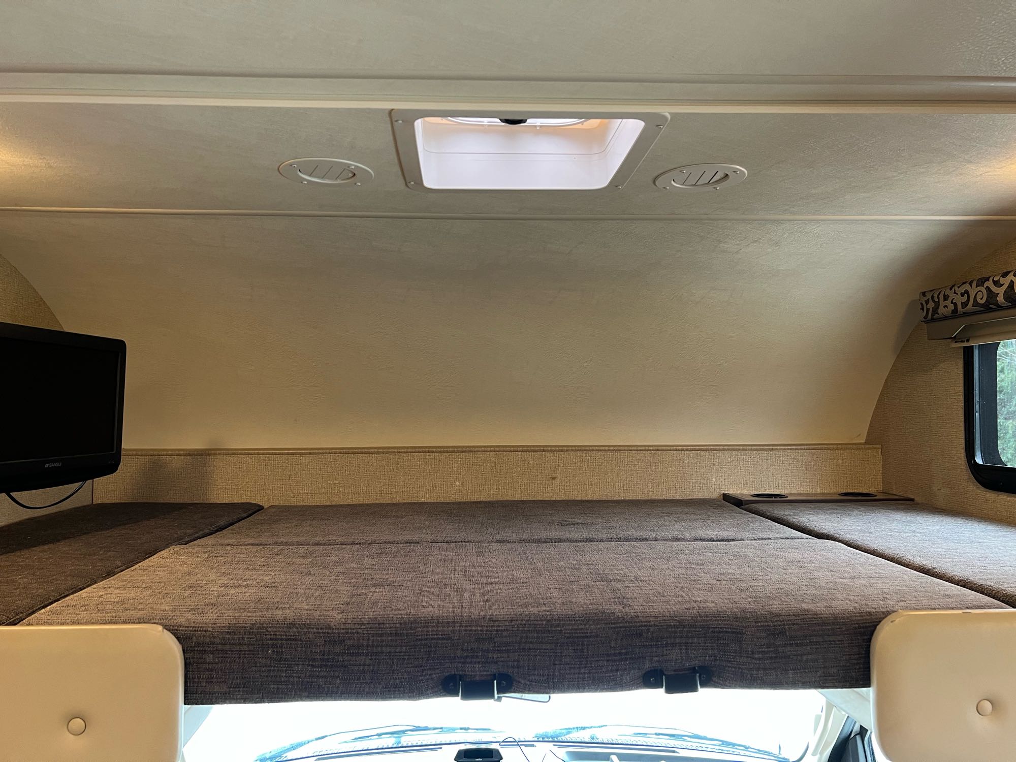 Inside RV rental: Spacious overhead bunk bed with mattress, TV, ceiling vents, and window for cozy travel.. Thor Motor Coach Four Winds 2018