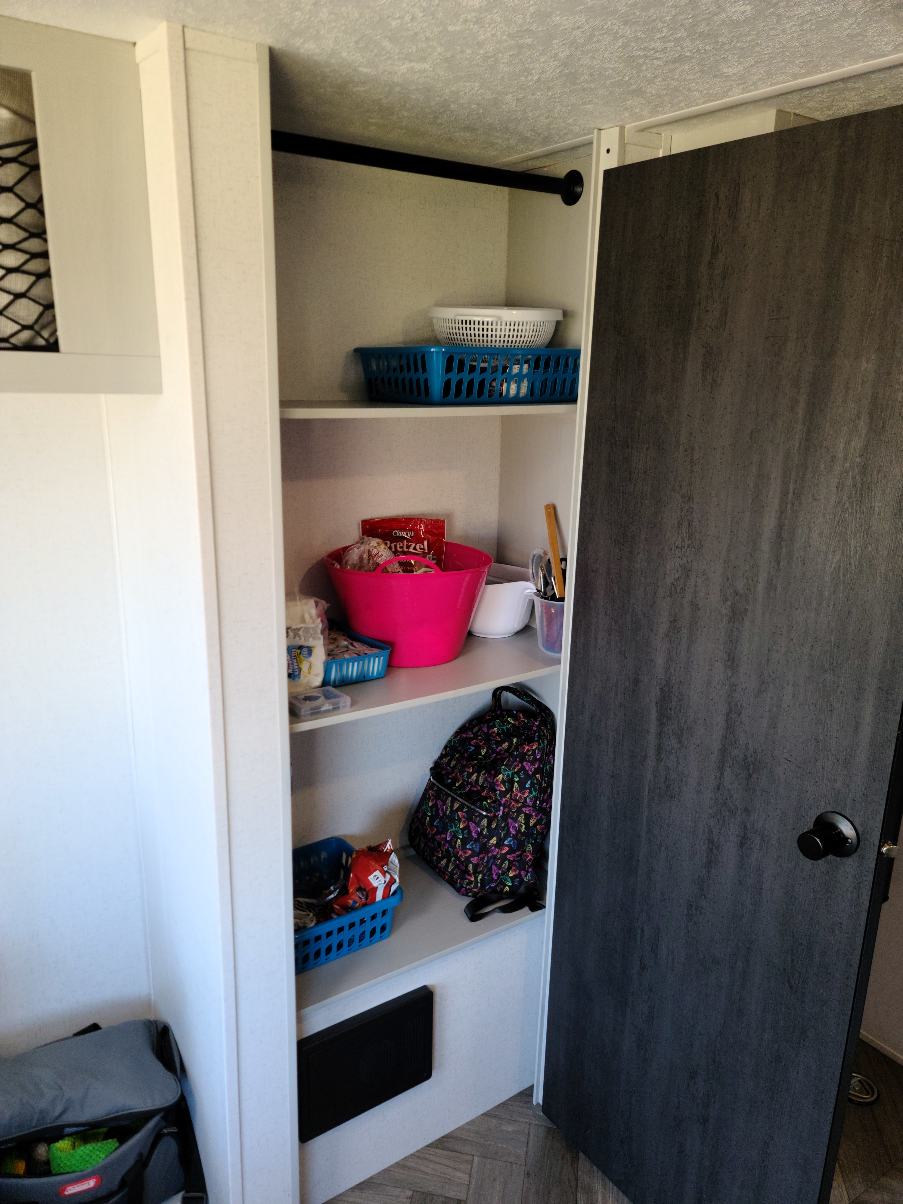 Organized storage in an RV rental, featuring shelves with baskets, snacks, kitchenware, and a butterfly backpack.. Forest River Salem 2022