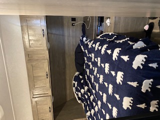 This RV rental bedroom shows a bed with a cozy bear blanket, modern cabinets, and a comfortable interior, ready for travel.. Forest River Vibe 2020