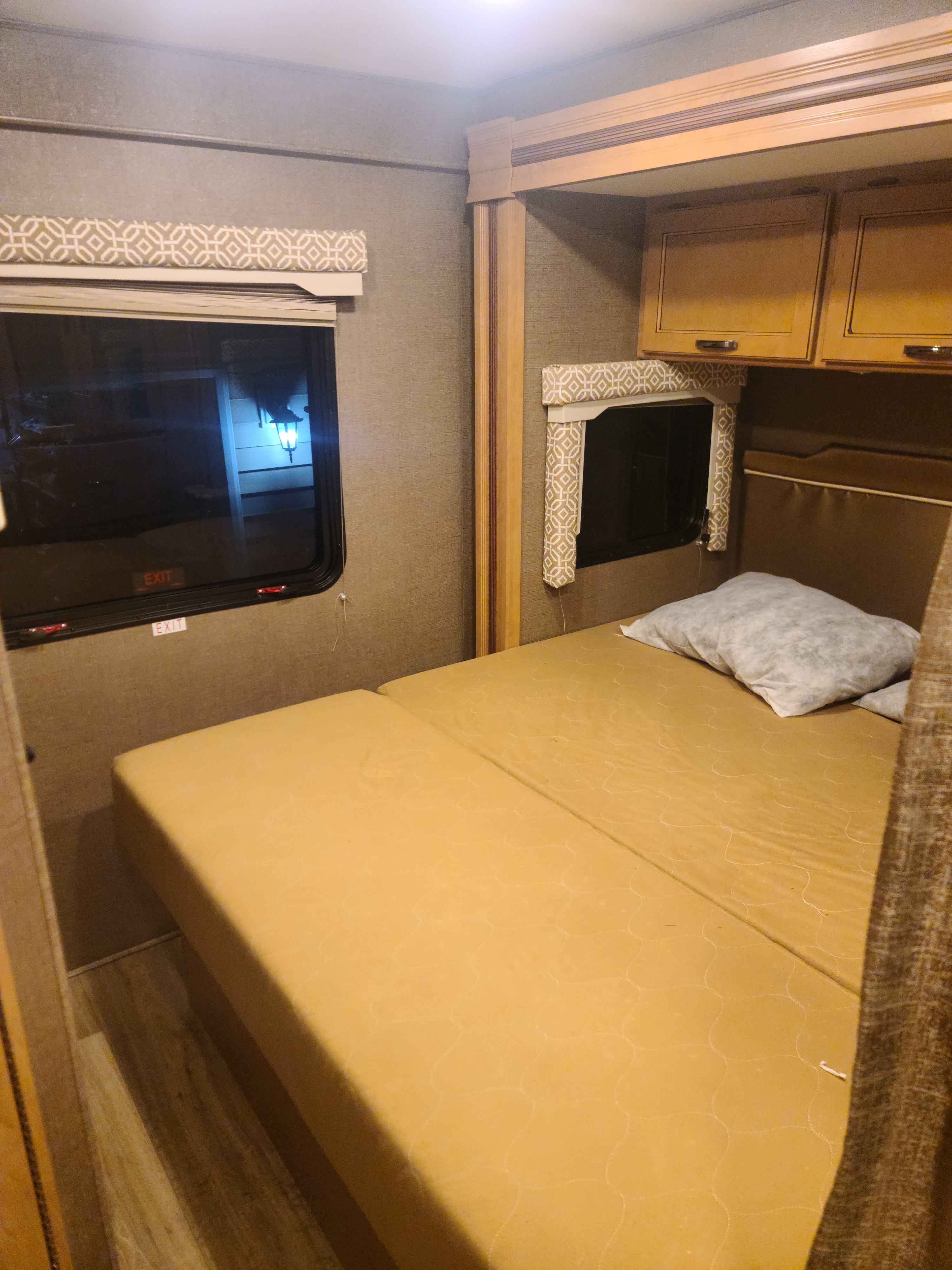 Cozy RV rental bedroom with a comfortable bed, overhead cabinets, and windows. Perfect for travel.. Thor Motor Coach Freedom Elite 2017
