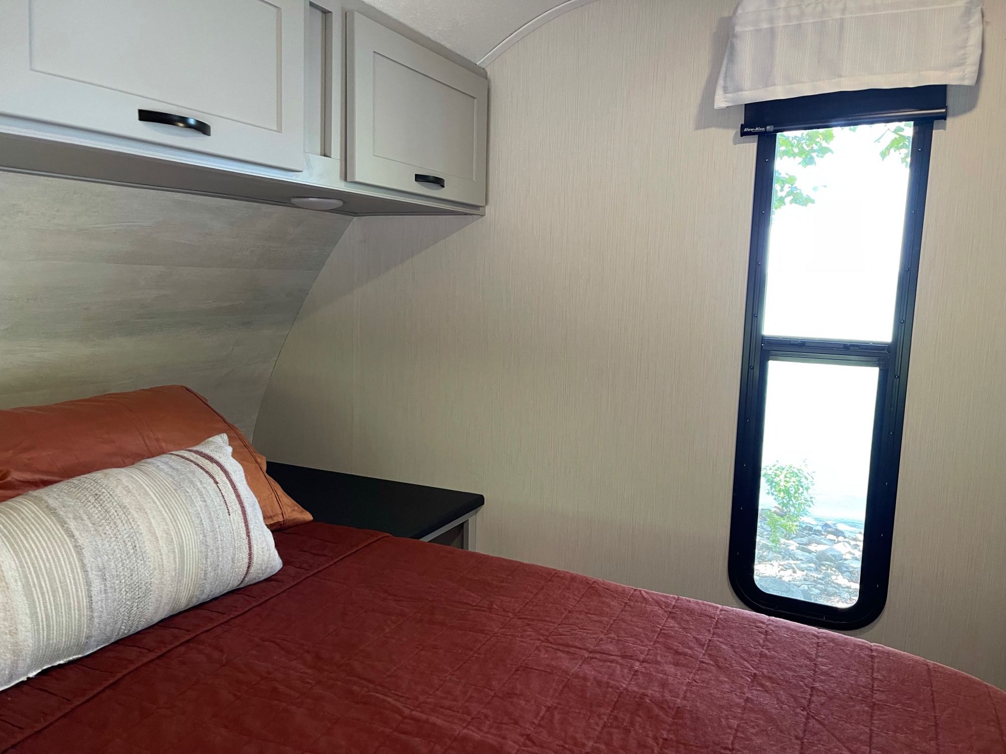 Relax in this cozy RV rental bedroom. Features a comfy bed, cabinets, and a scenic window view of nature.. Forest River Vibe Travel Trailer 2022