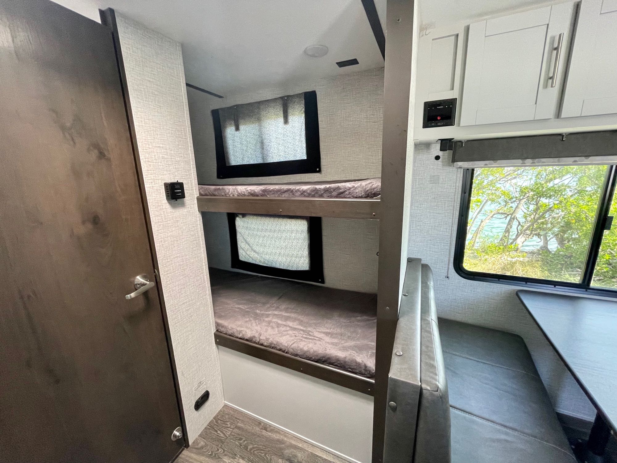 Inside an RV rental: comfortable bunk beds, a dinette area, and beautiful waterfront views.. Keystone RV Bullet Crossfire 2021