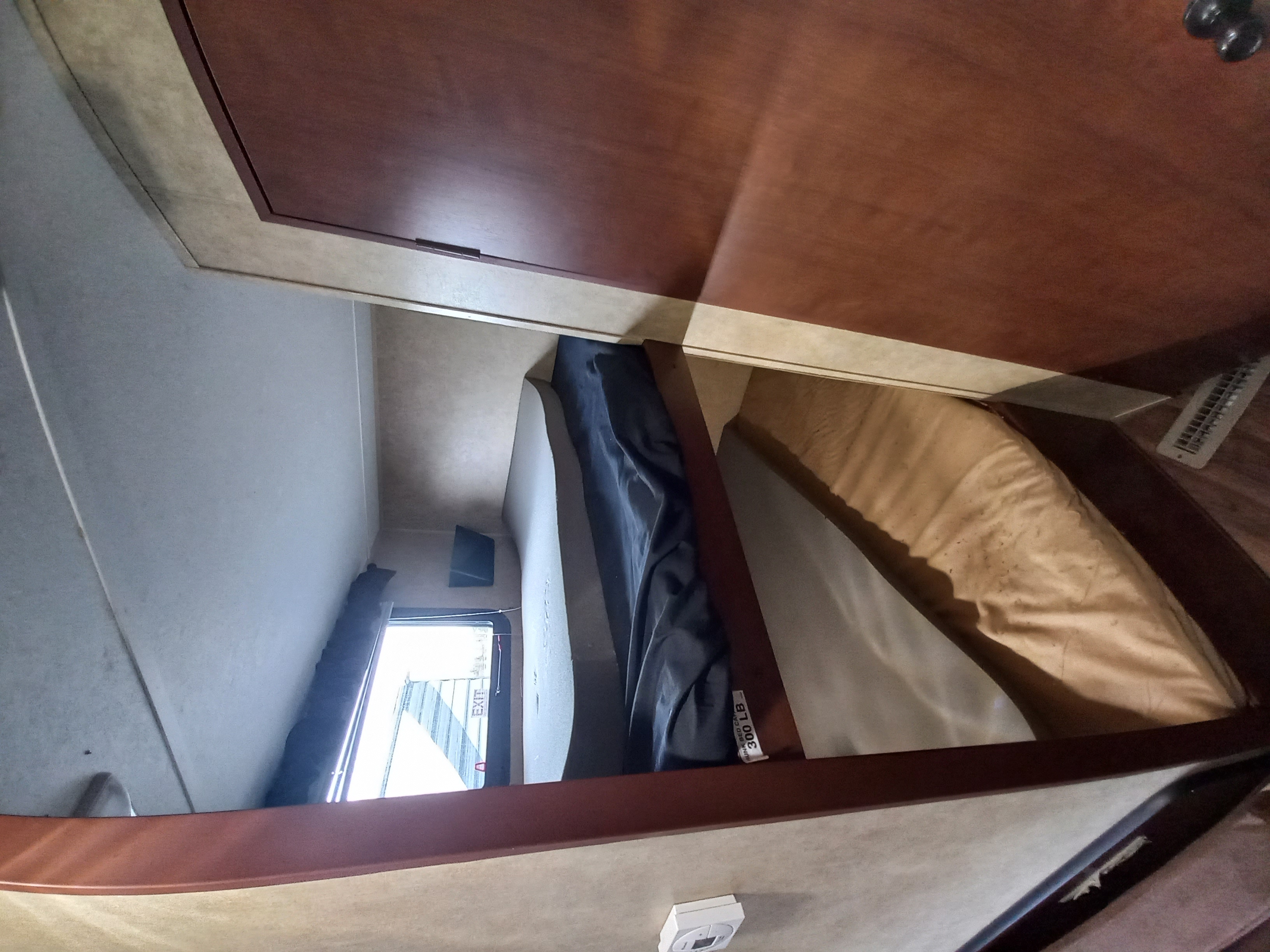 RV rental interior: view of two stacked mattresses, wood accents, wall paneling, and an exit window in the sleeping area.. Aspen Trail Aspen Trail Trailer 2012